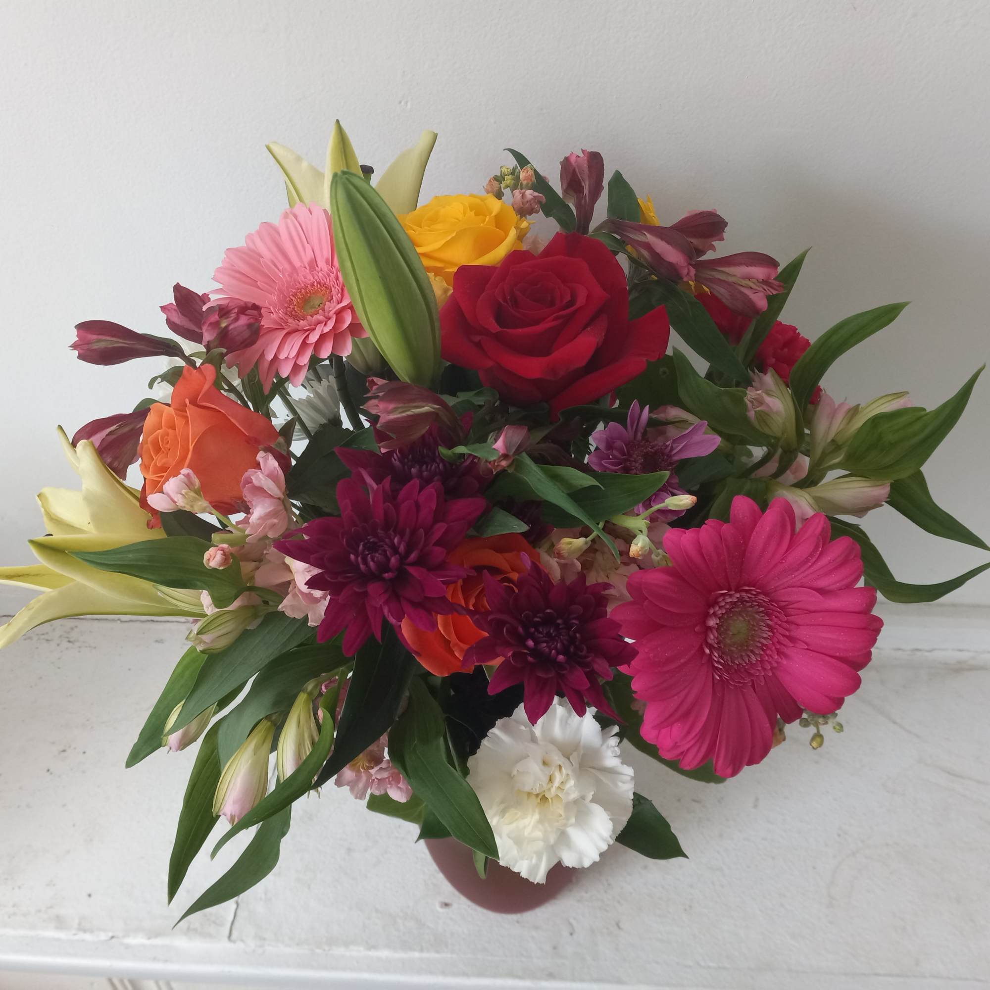 Beautiful fresh deep bright burgundy daisies, various roses and sparkly pink and