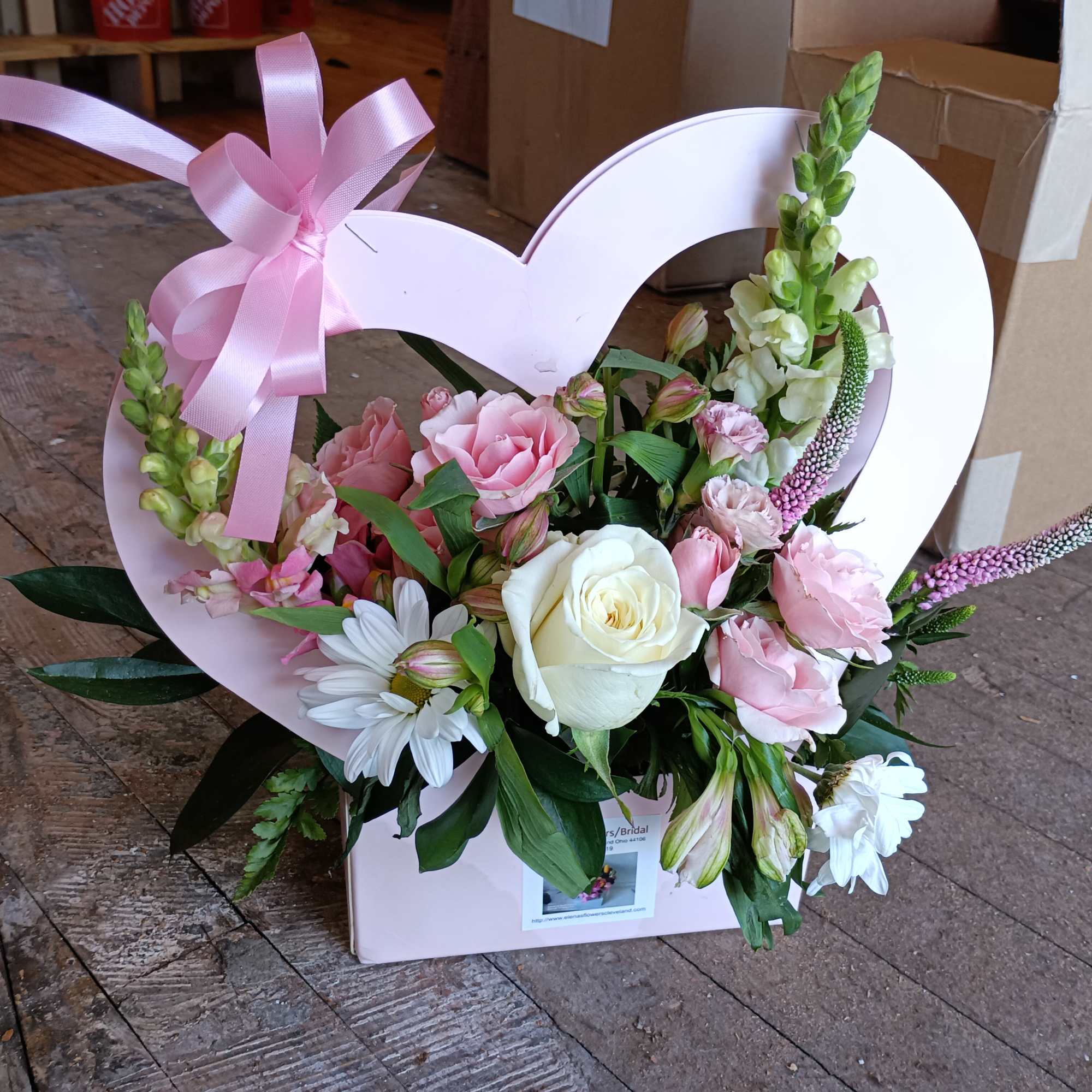 Festive heart shaped paper basket arranged with pink spray roses, veronica, alstroemeria