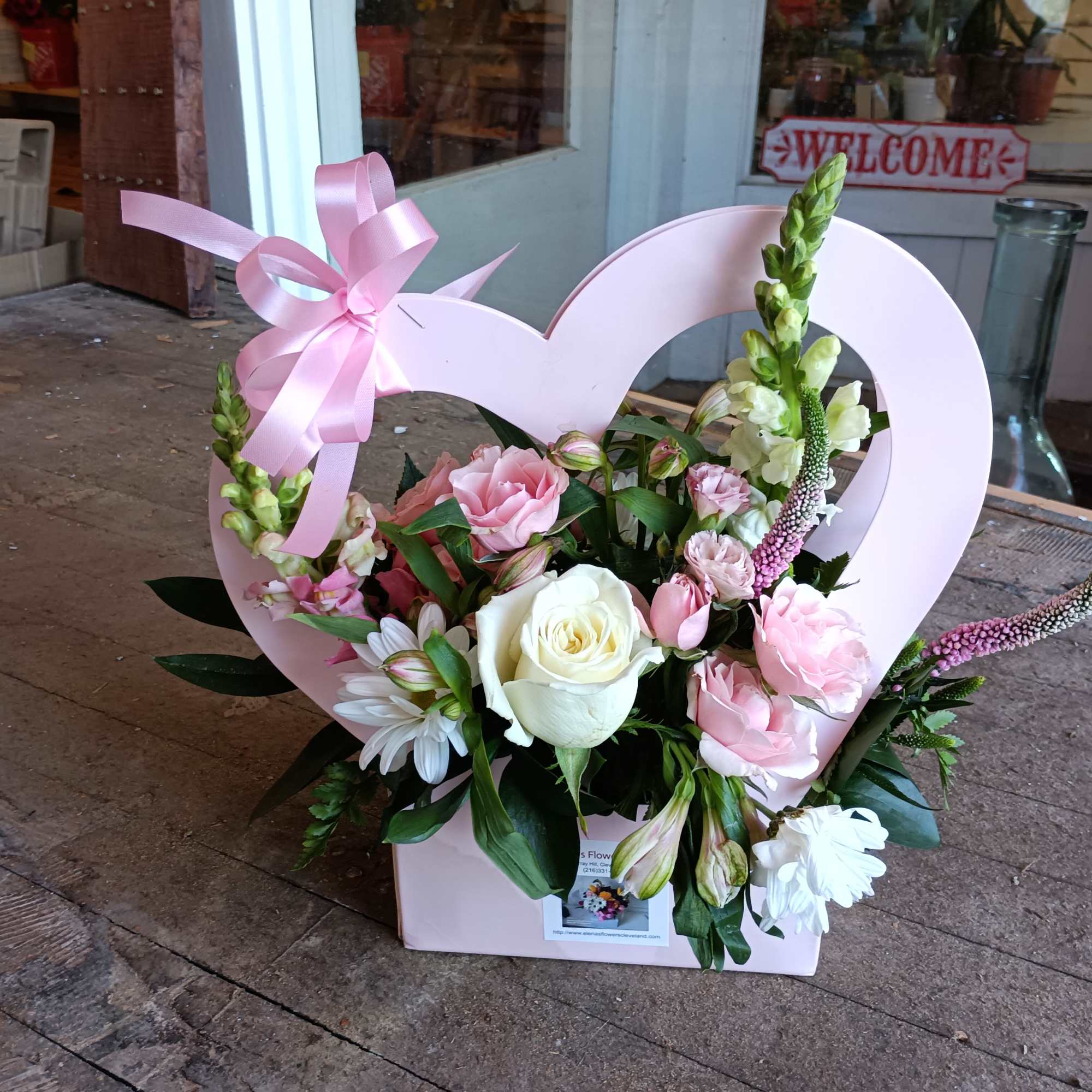 Festive heart shaped paper basket arranged with pink spray roses, veronica, alstroemeria