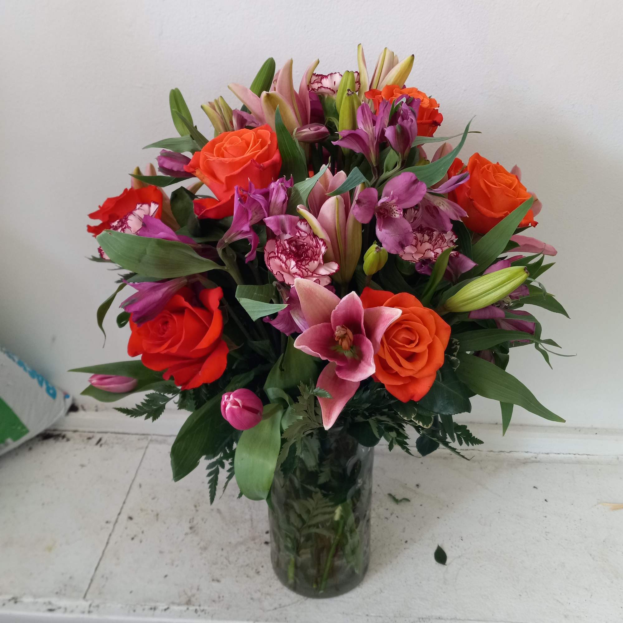 Beautiful orange roses mixed in with pink lilies, purple/pink alstroemeria and light