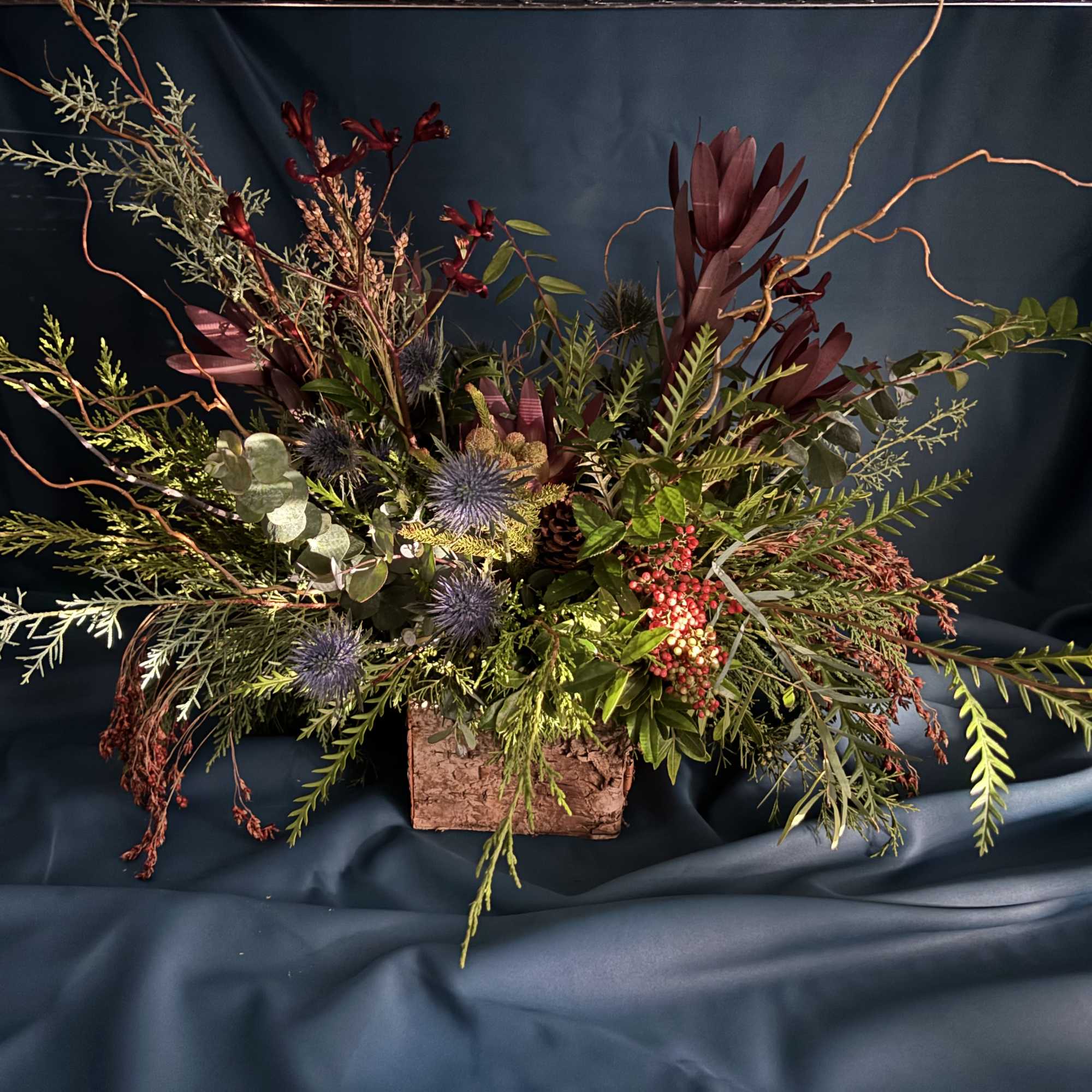 Indulge in an elegant arrangement of Christmas greens merged with holiday magic