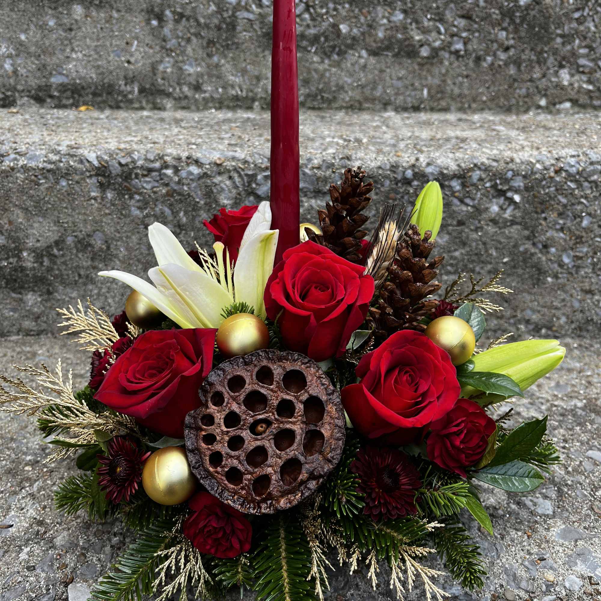 This arrangement has roses, lilies, Christmas ornaments, pinecones, mums , mini carns