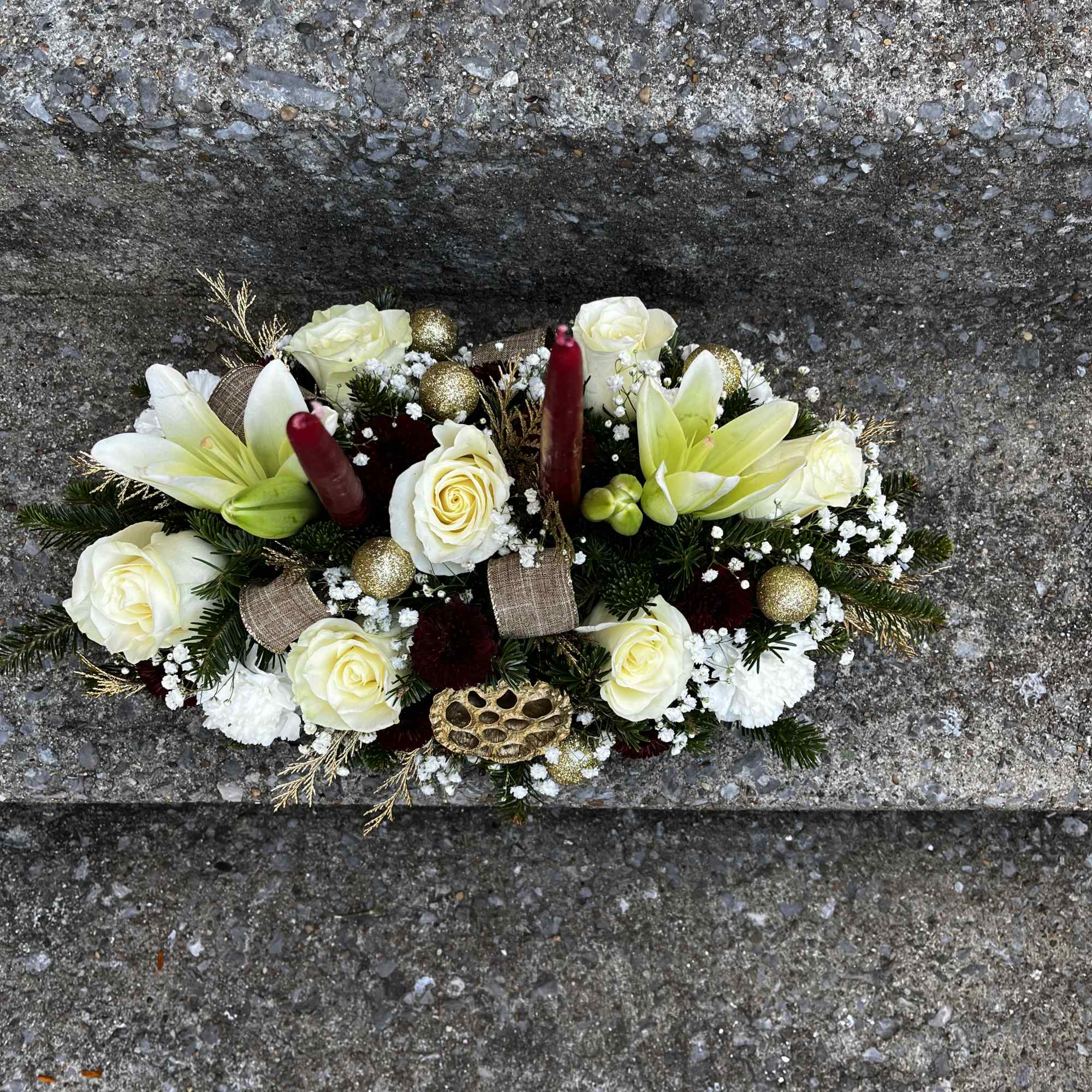 This centerpiece has lilies, roses, carnations, babies breath, pinecones, Christmas ornaments, Christmas