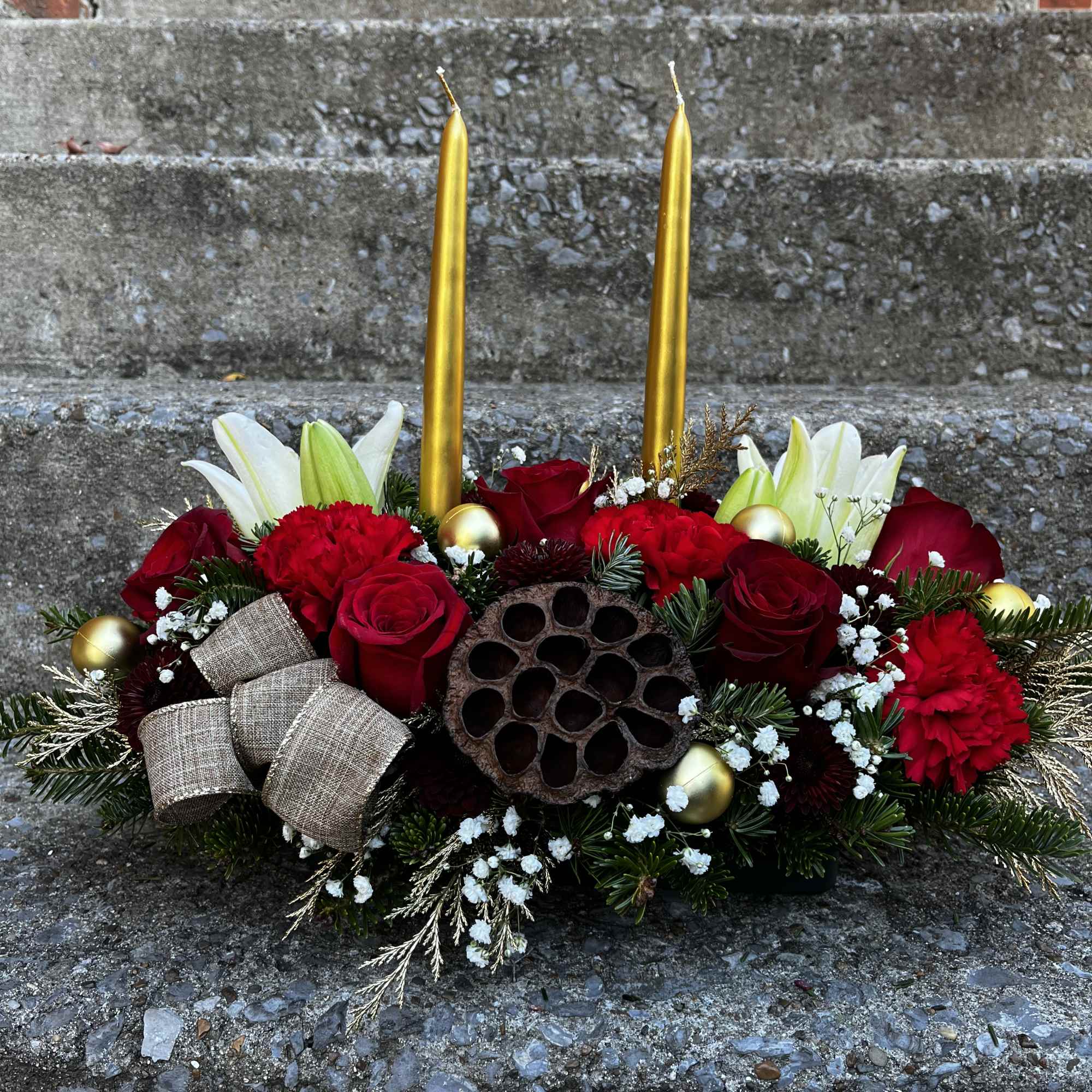 This centerpiece has roses, lilies, carnations, mums, a pinecones, ribbon Tuffs, Christmas