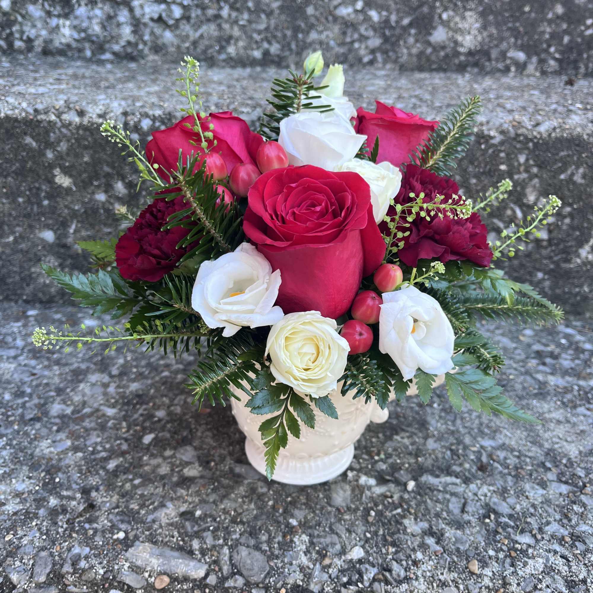 This arrangement has red roses, hypericum, spray roses, carnations and beautiful Christmas