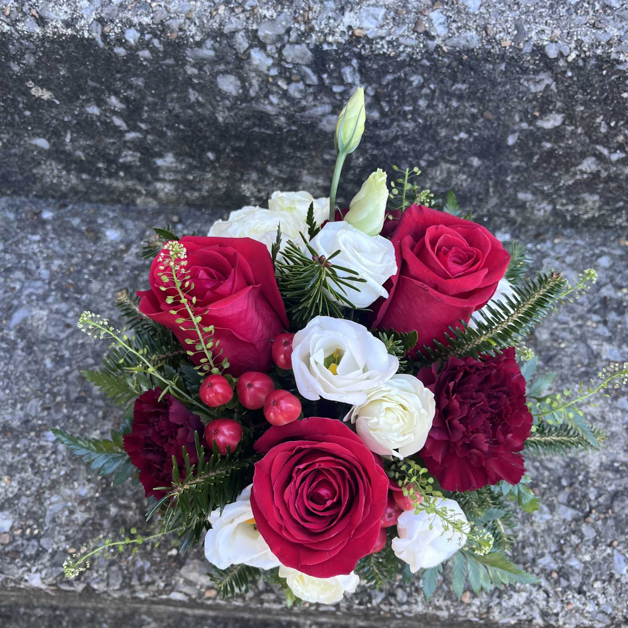 This arrangement has red roses, hypericum, spray roses, carnations and beautiful Christmas