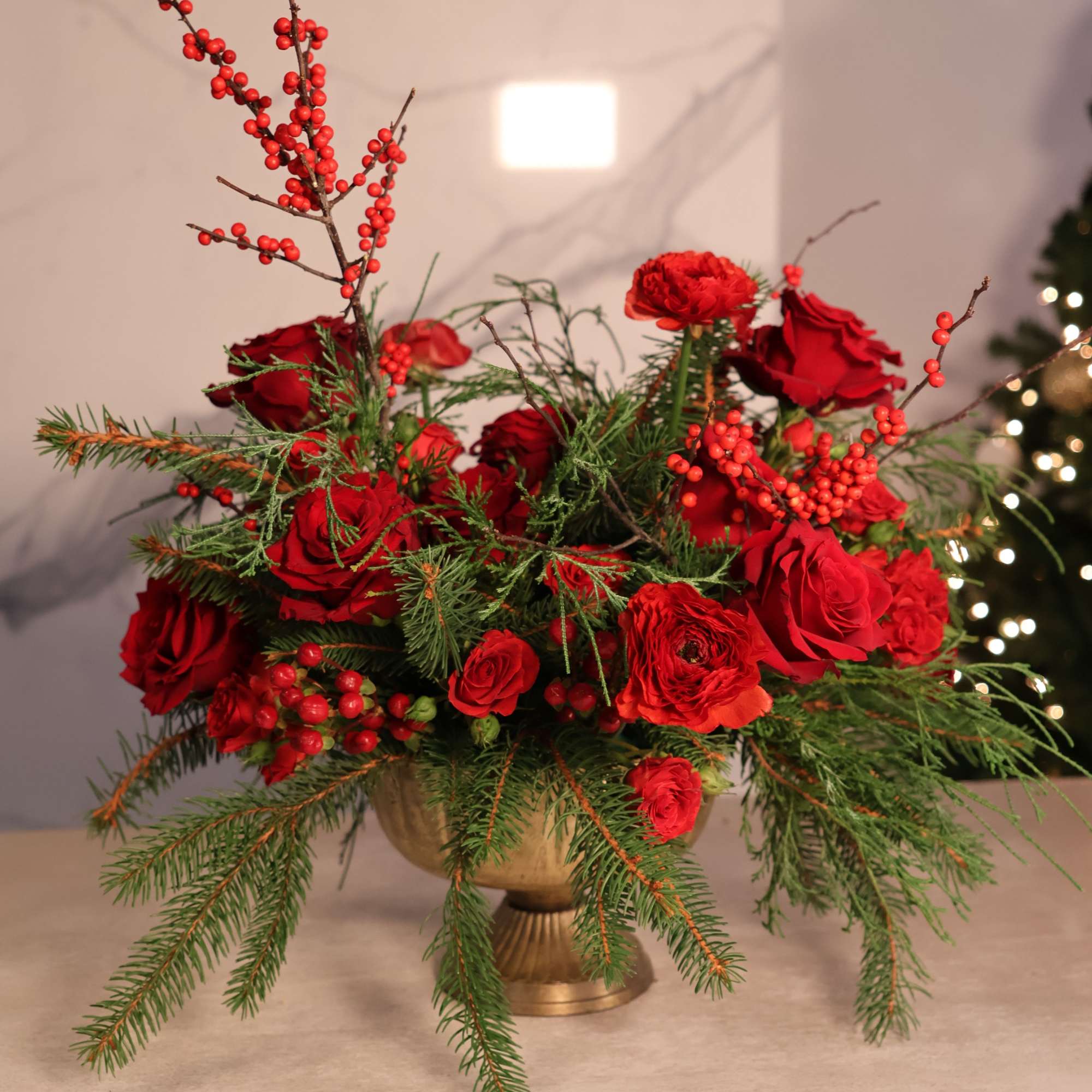 A rich, dramatic Christmas centerpiece overflowing with vibrant red blooms and lush
