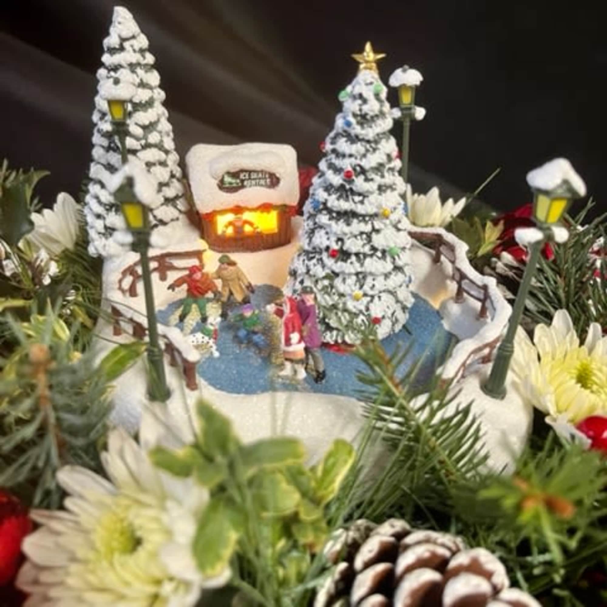 A vintage Thomas Kinkade ice skating rink adorned with Winter greens, pinecones