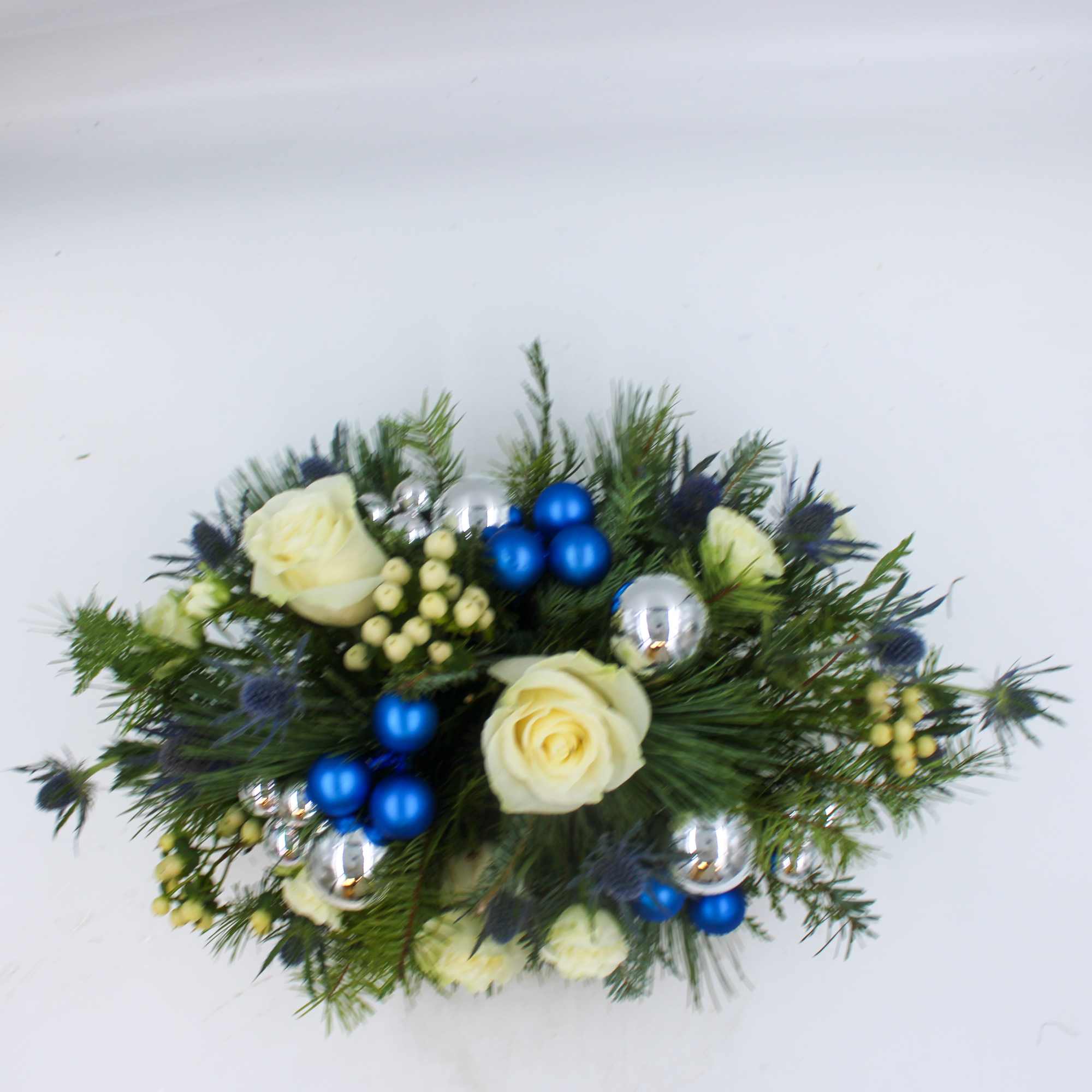 Blue Christmas is a luxurious centerpiece with beautiful Blue Thistle, White Roses