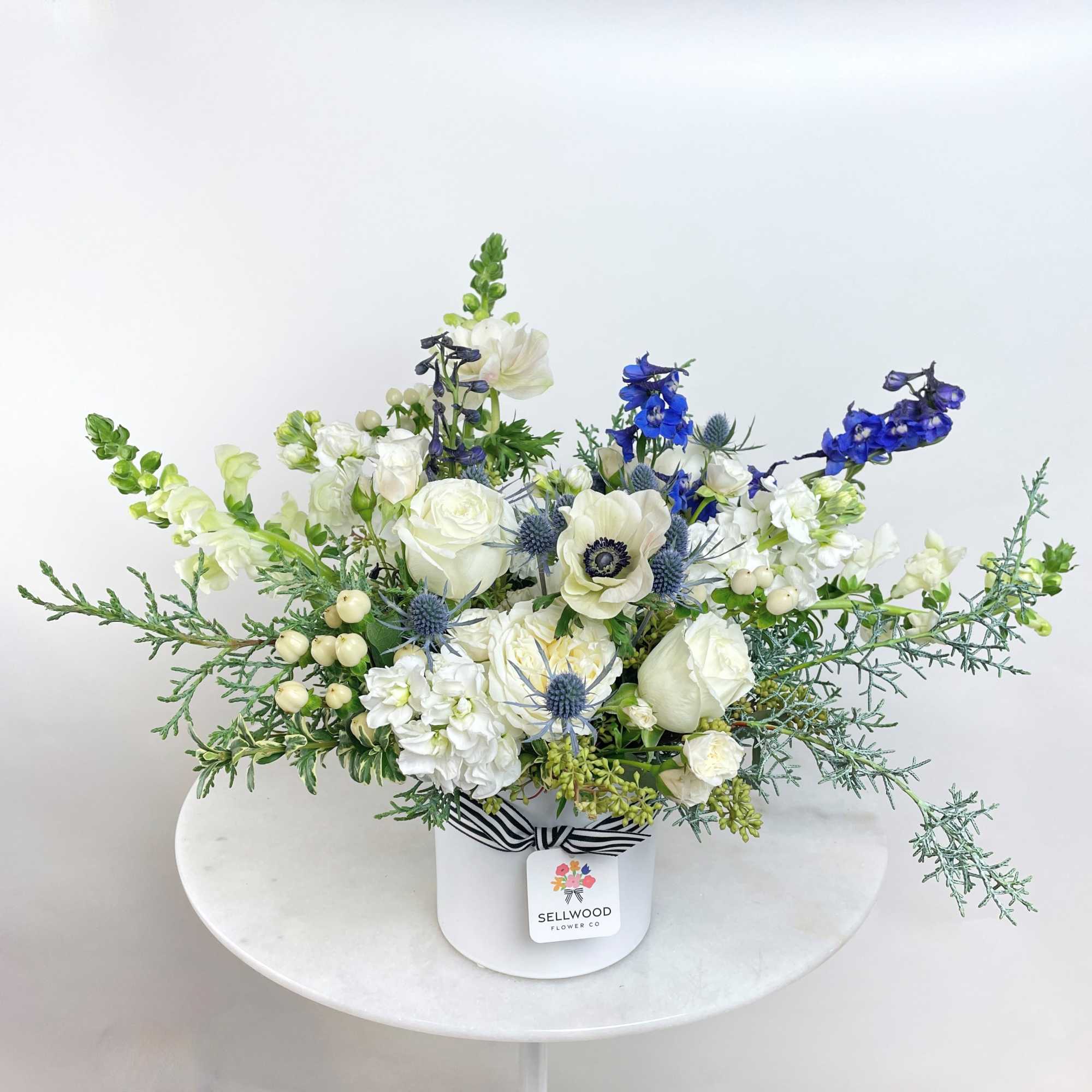 Elegant and refreshing, this arrangement features lovely white blooms, vibrant blue delphiniums