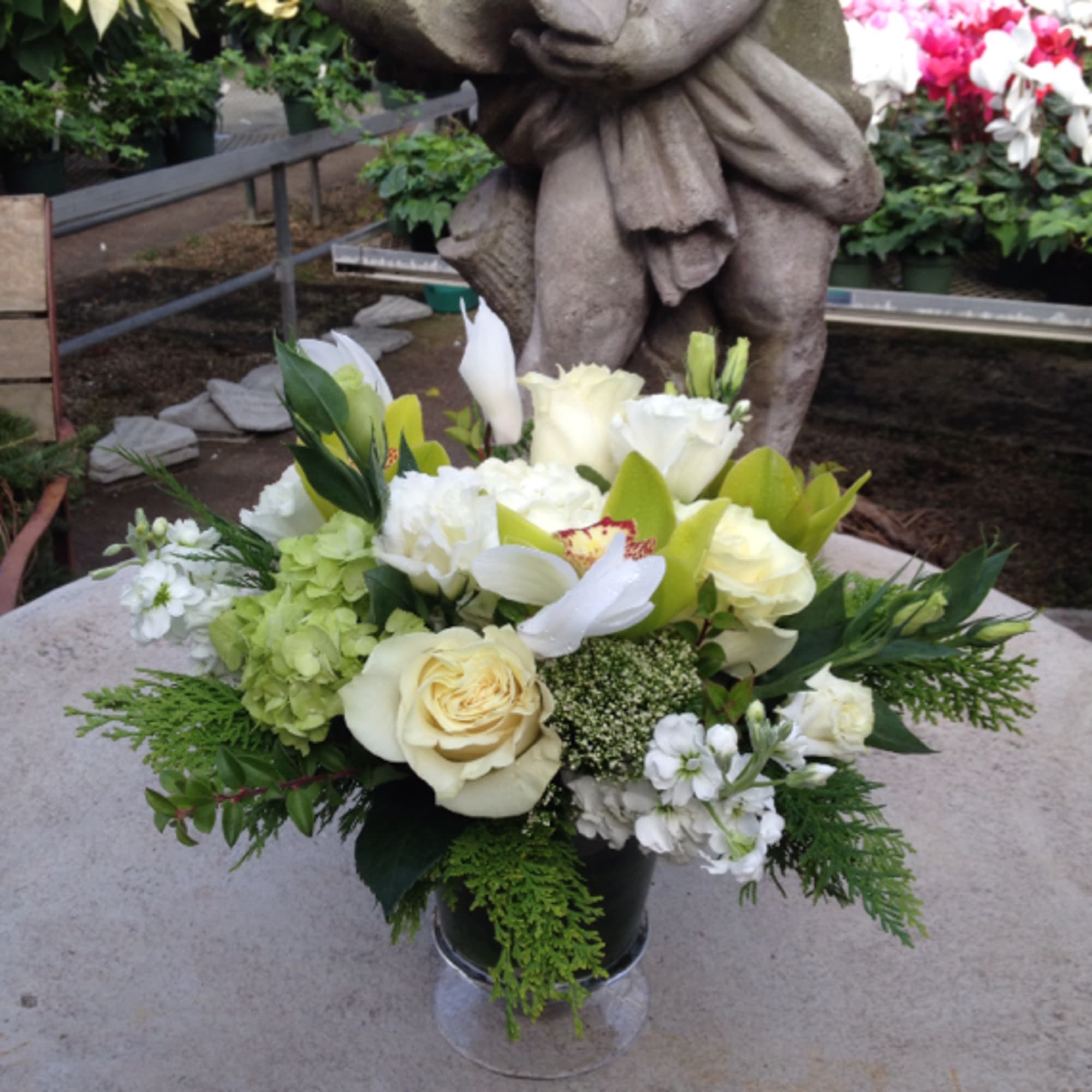 Cymbidiums and roses make up this beautiful arrangement comprised in an urn.
