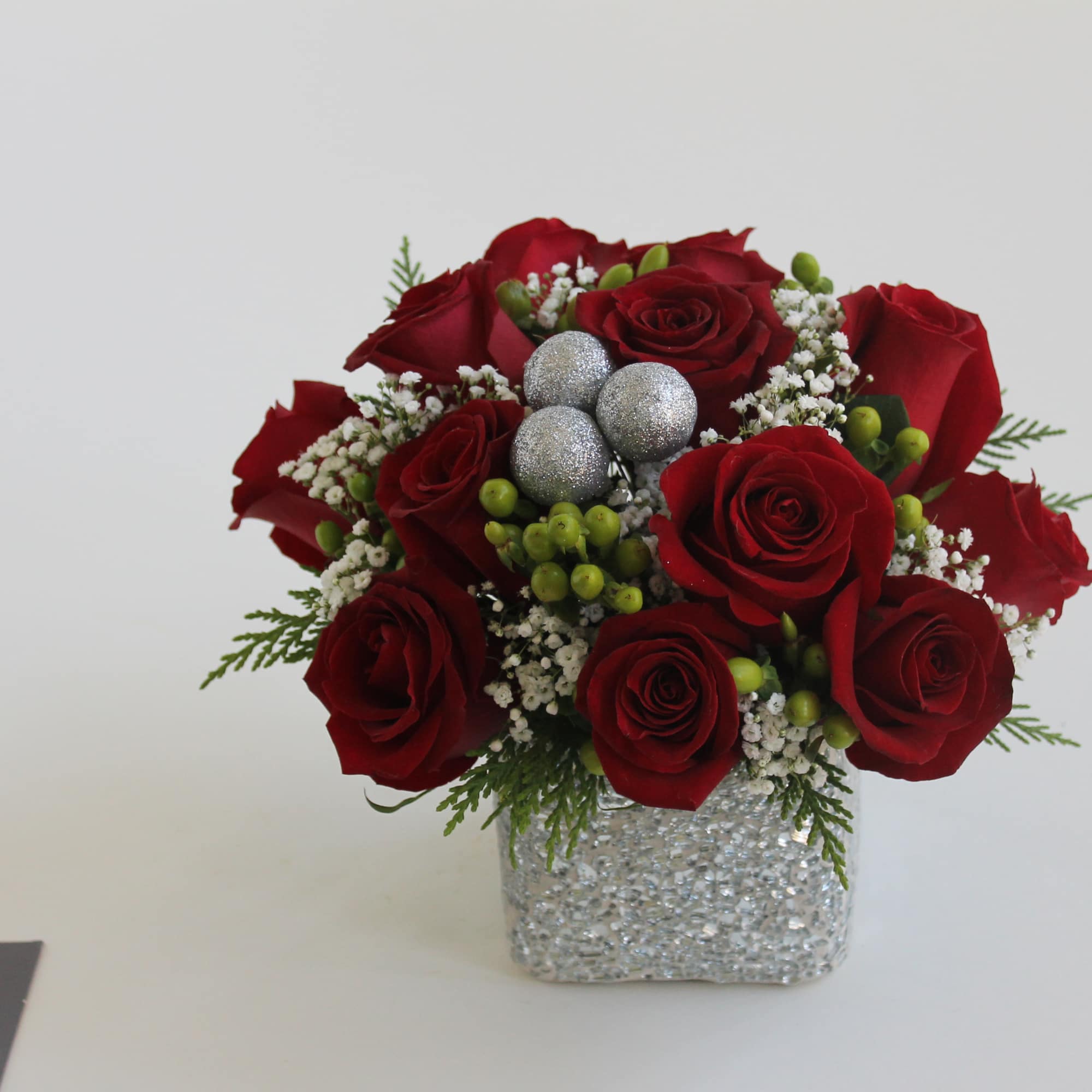 Send your Christmas love with this hand-tied centerpiece of red roses, snowy