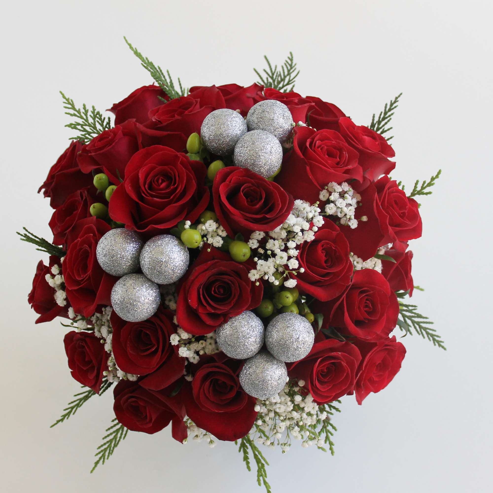 Send your Christmas love with this hand-tied centerpiece of red roses, snowy