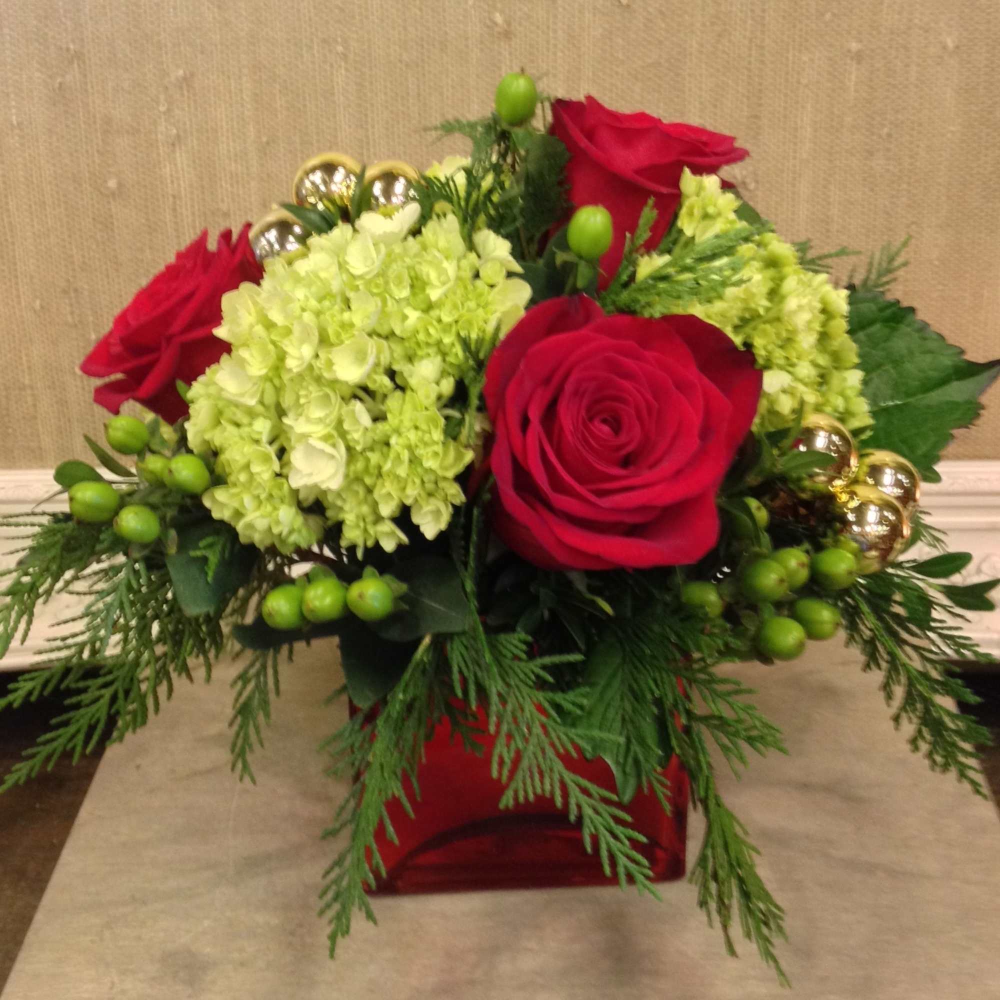 Green Hydrangea, Red Roses, Festive balls and Red Hypericum are nestled in