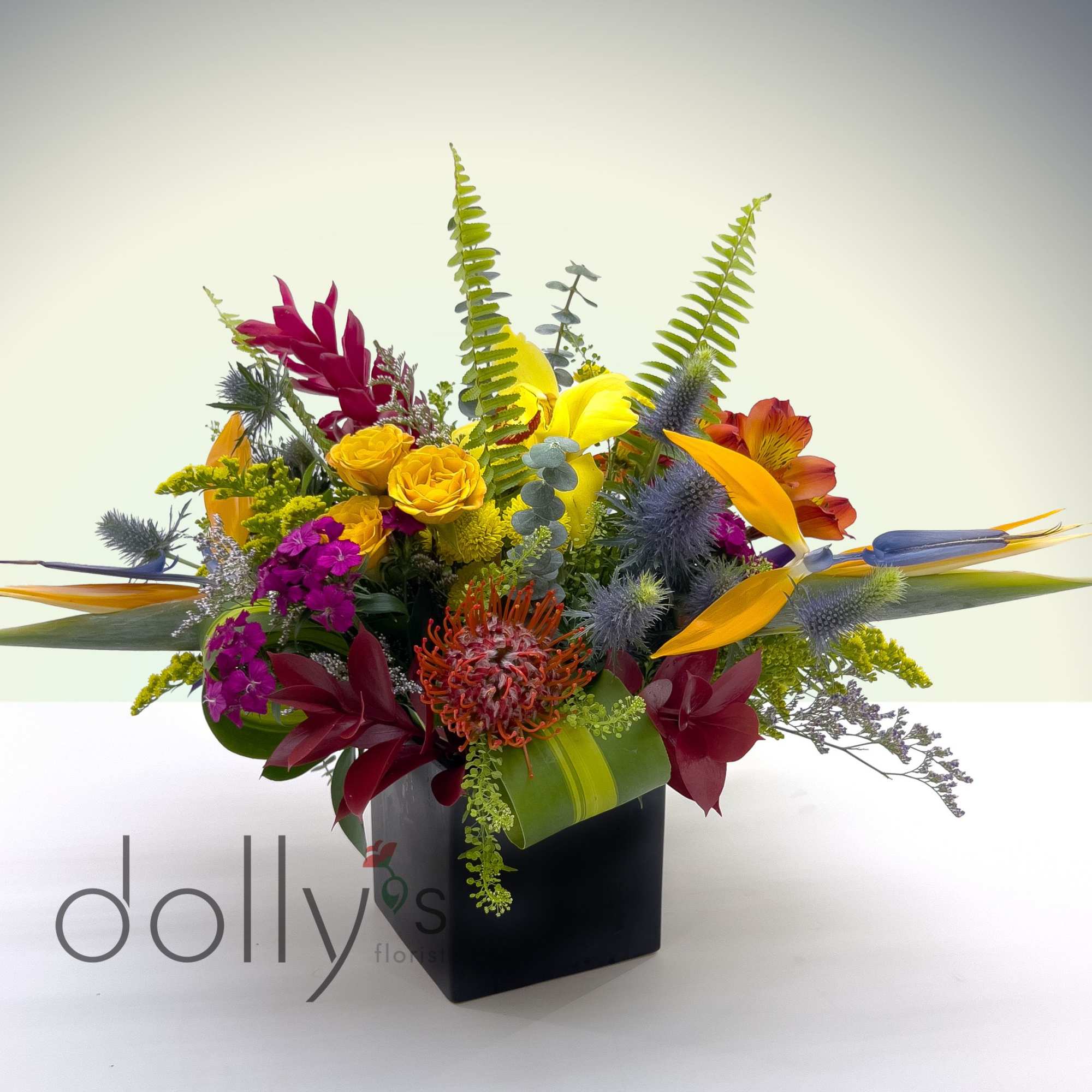 A lush centerpiece held in a large cube vase.