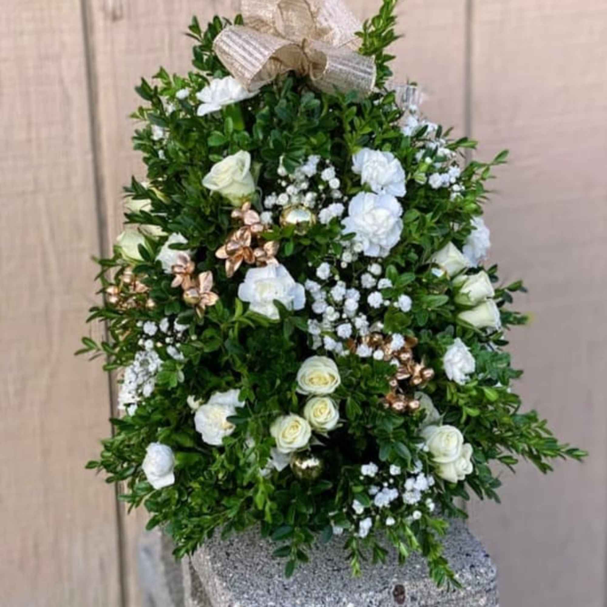 A table top tree adorned with fresh Christmas greens, fresh flowers, berries