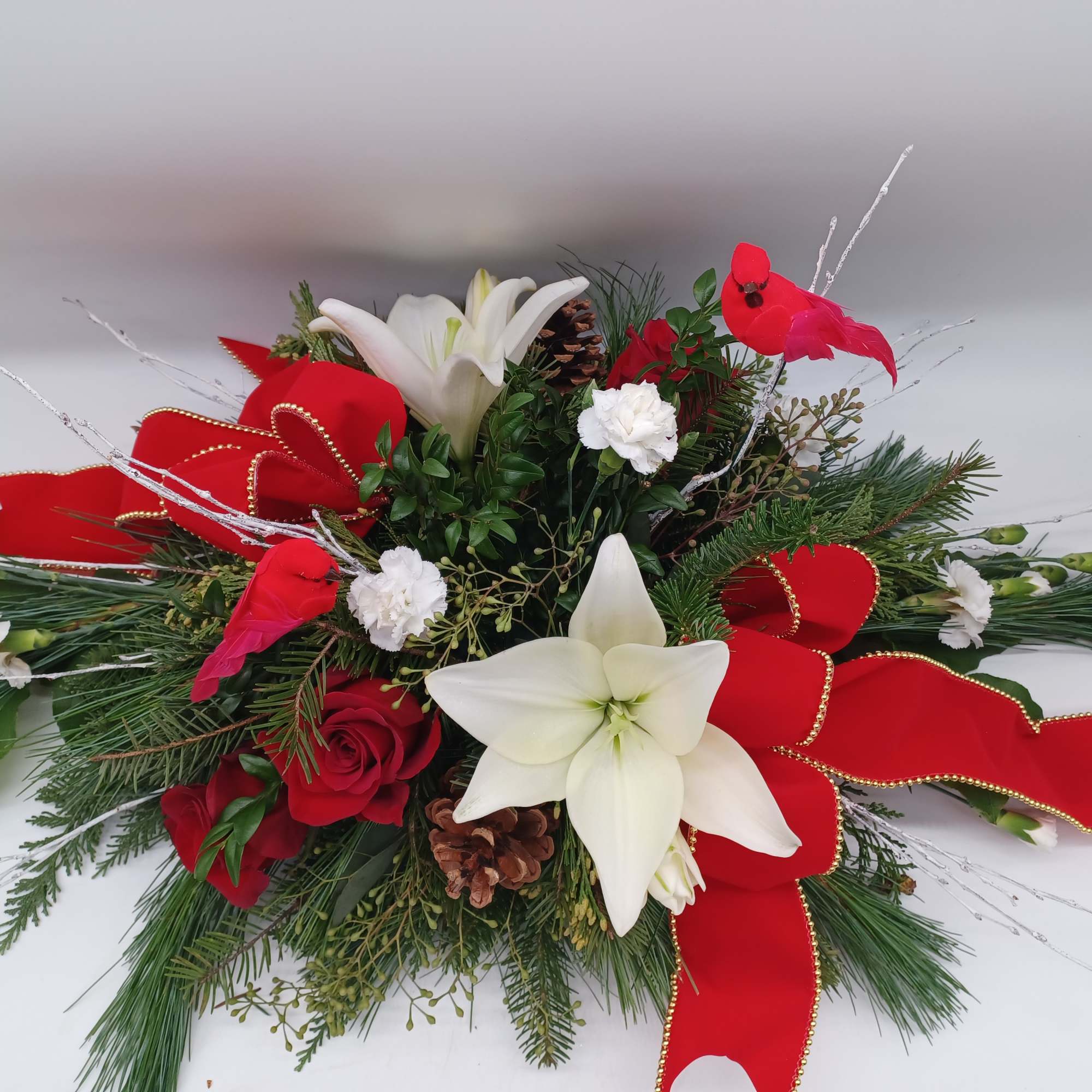 A mix of evergreens and selected flowers such as Hybrid White Lilies