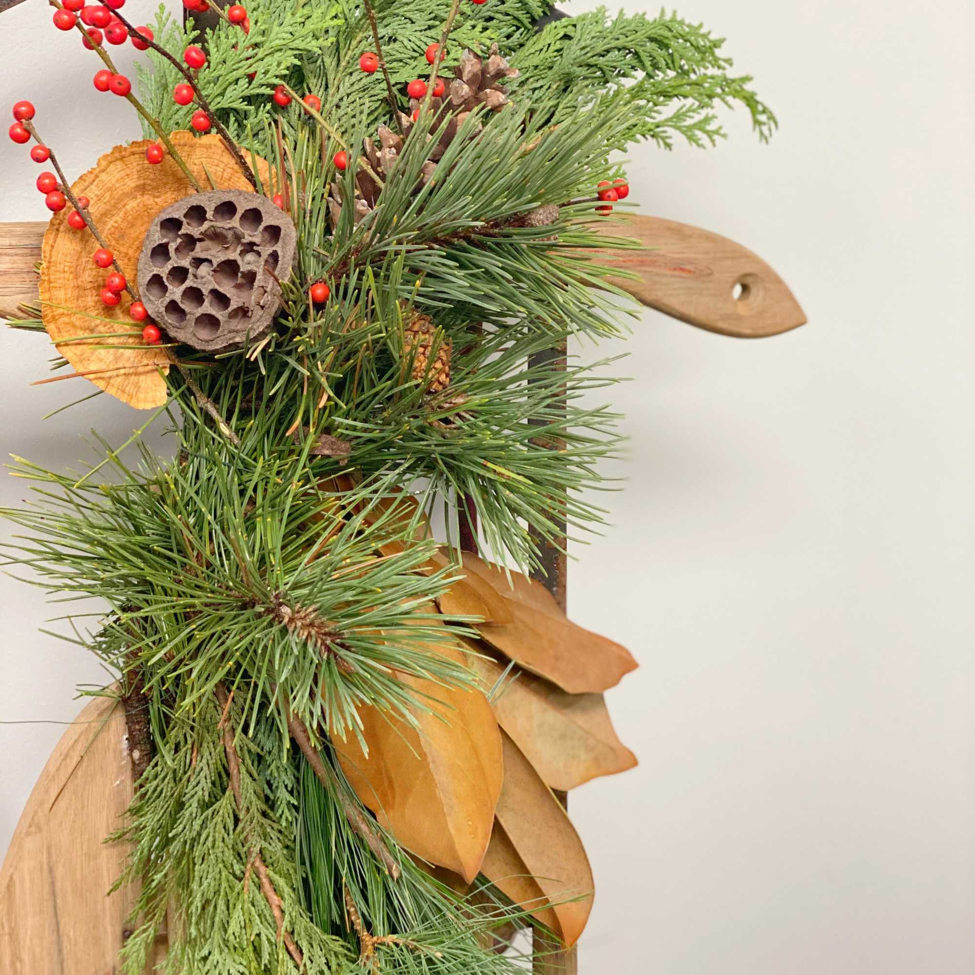 Vintage sled decorated with Christmas greens, magnolia, pinecones, etc. Perfect for front