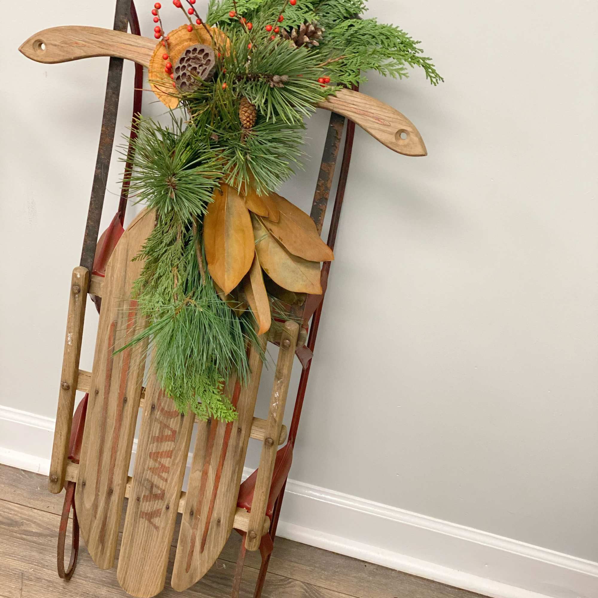 Vintage sled decorated with Christmas greens, magnolia, pinecones, etc. Perfect for front