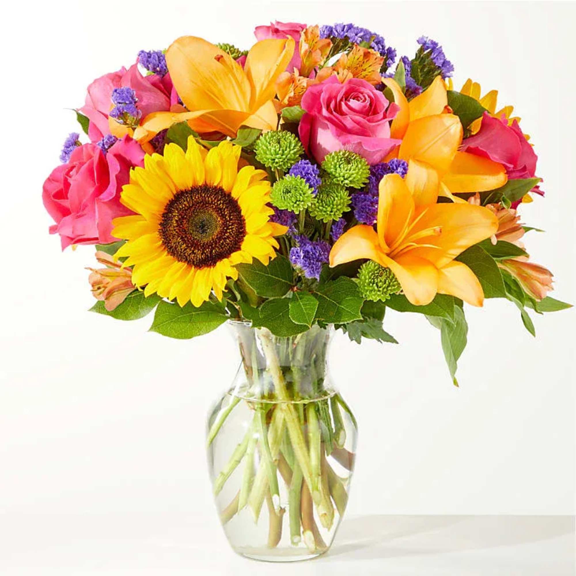 Vase Arrangement Of Lilys, Sunflowers, Roses, Buttons, Alstromeria, Statice And Lush Greenery.