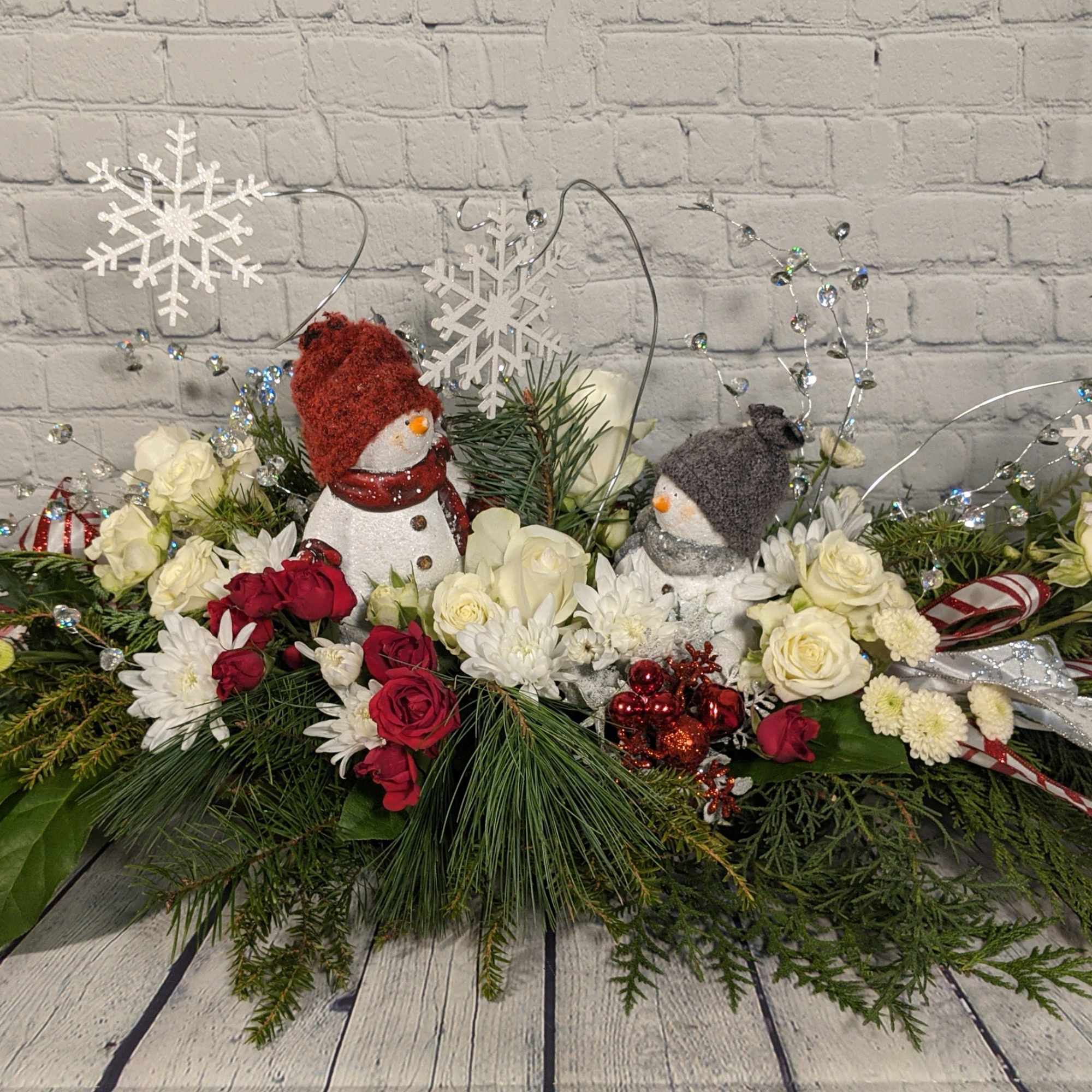 The adorable holiday bouquet is filled with pure white flowers, mixed pine