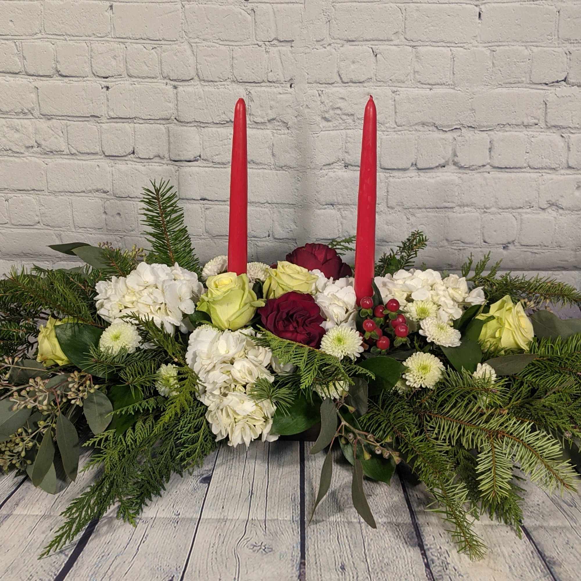 A traditional Christmas centerpiece, complete with roses, stock, hypericum, chrysanthemums, and a
