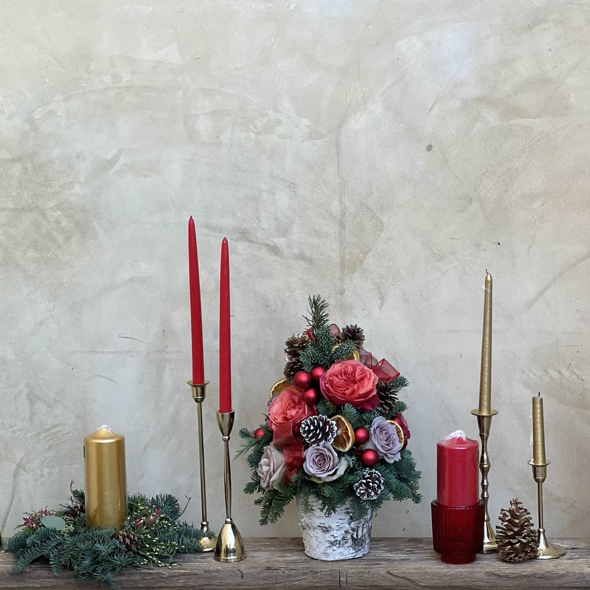Fresh tabletop Christmas foliage adorned in real roses, pinecones, ribbon and baubles.