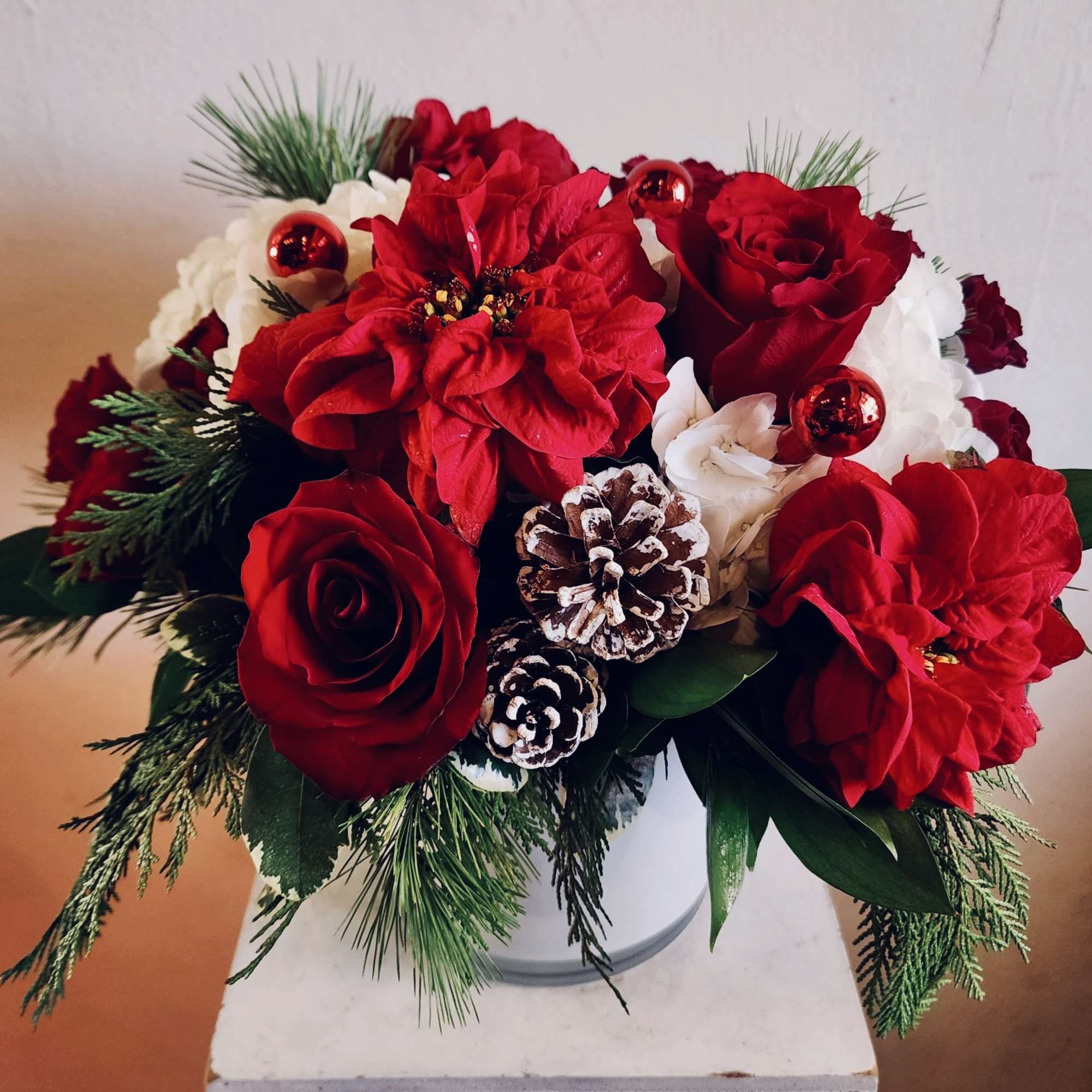 White hydrangea, red roses, winter rose poinsettias, accents of ornaments and pine