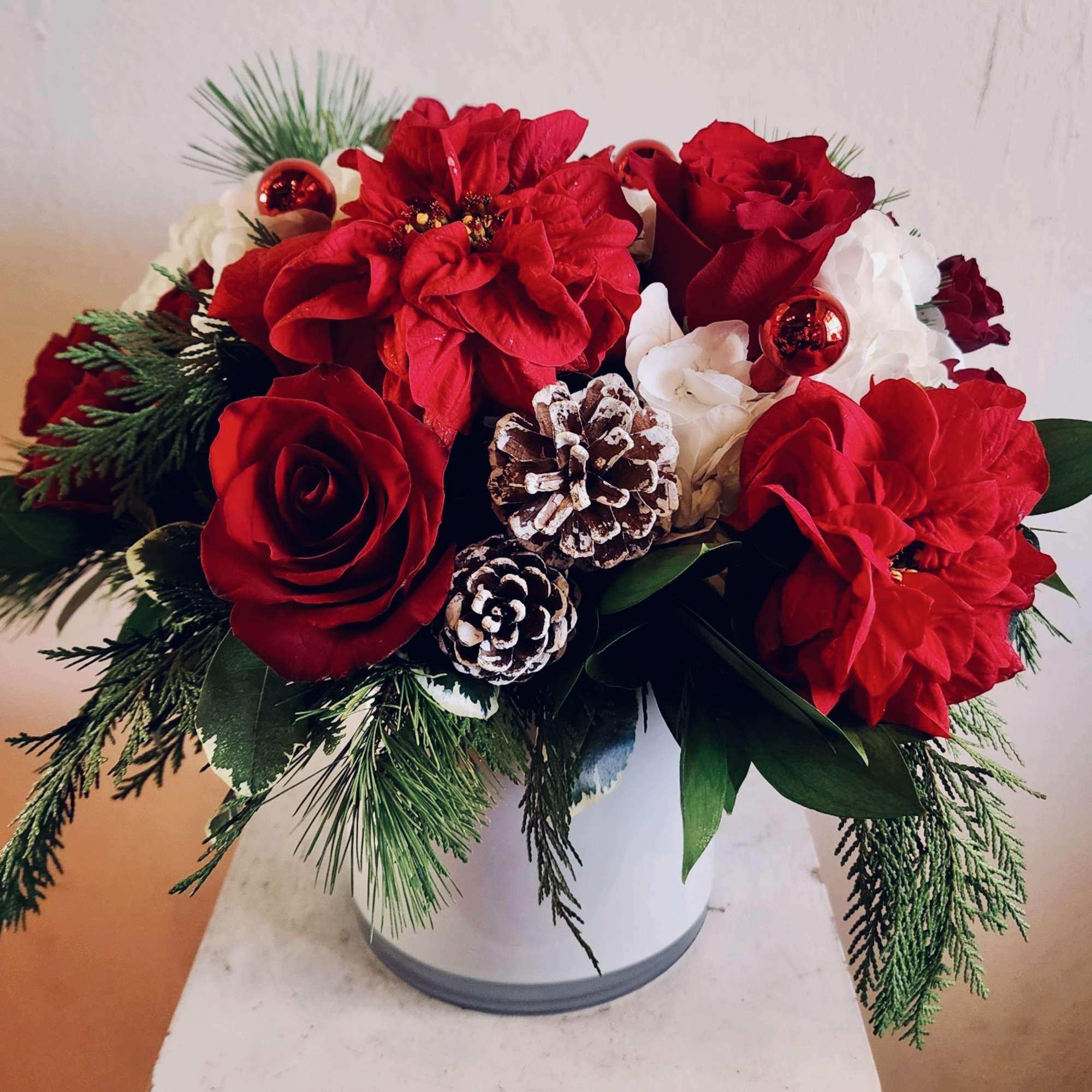White hydrangea, red roses, winter rose poinsettias, accents of ornaments and pine