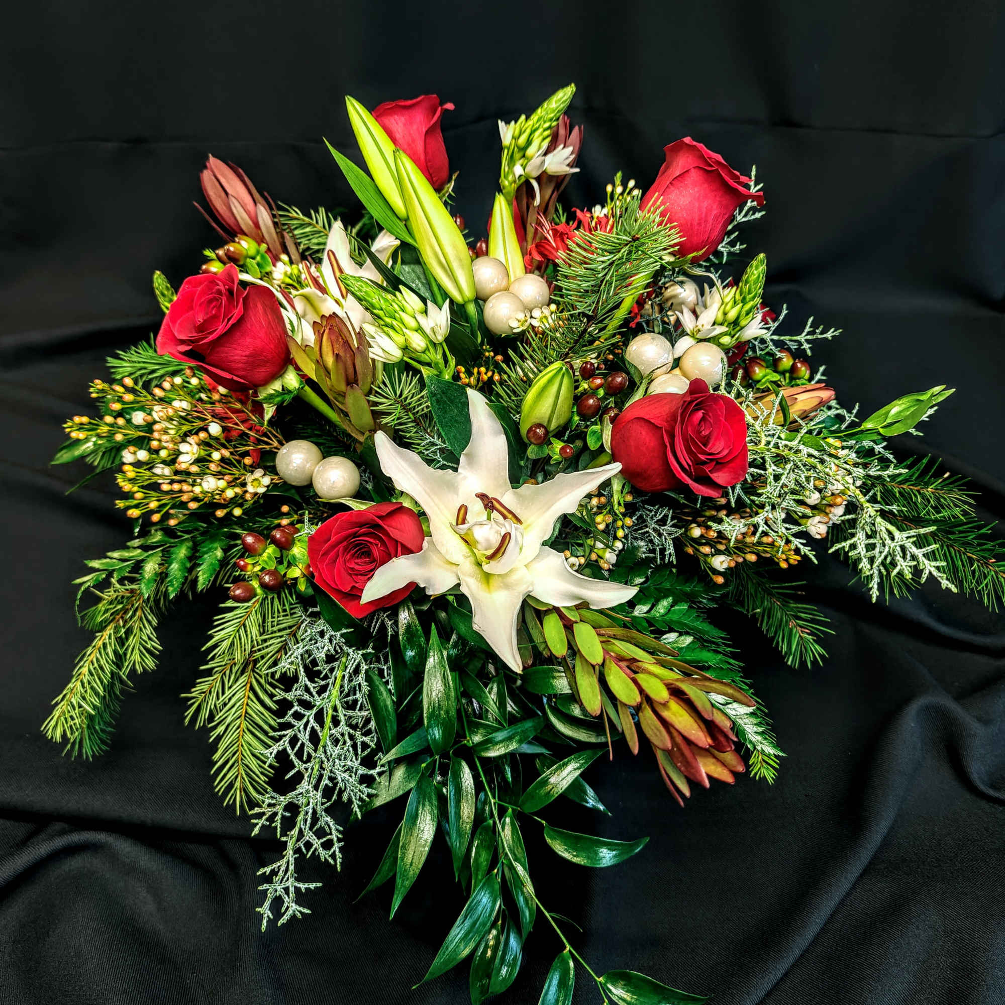 Luxurious red roses and ball ornaments with seasonal flowers create an exquisite