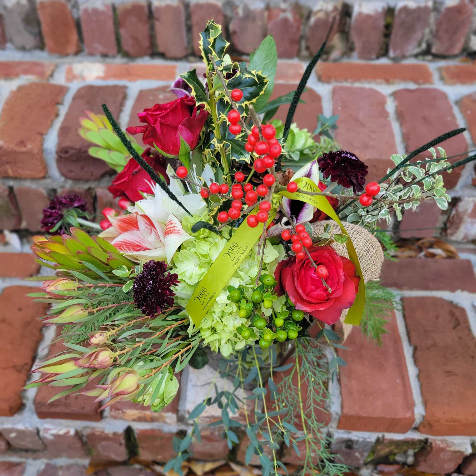 Seasonal arrangement featuring holly branches and other seasonal foliage combined with fresh