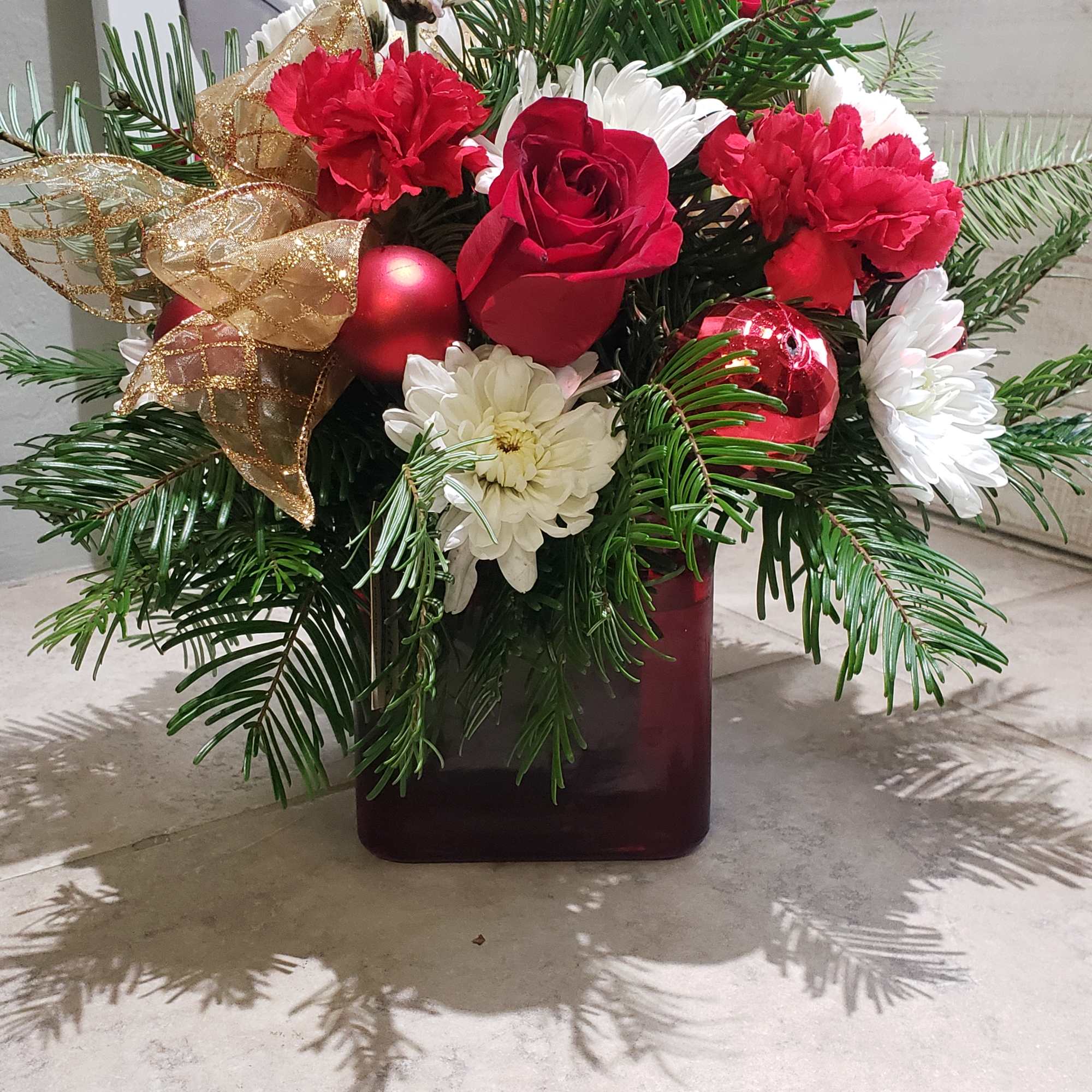 A sweet  Holiday mix of seasonal blooms and winter greens. 