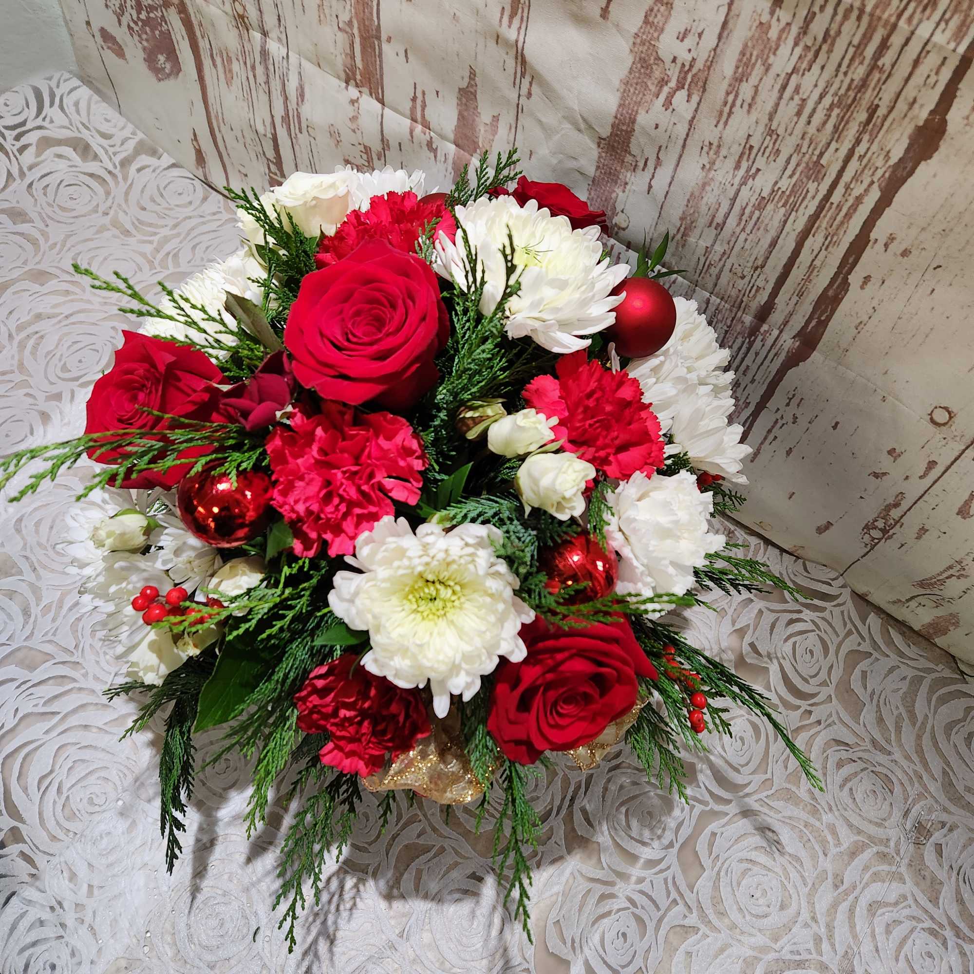 A sweet  Holiday mix of seasonal blooms and winter greens. 