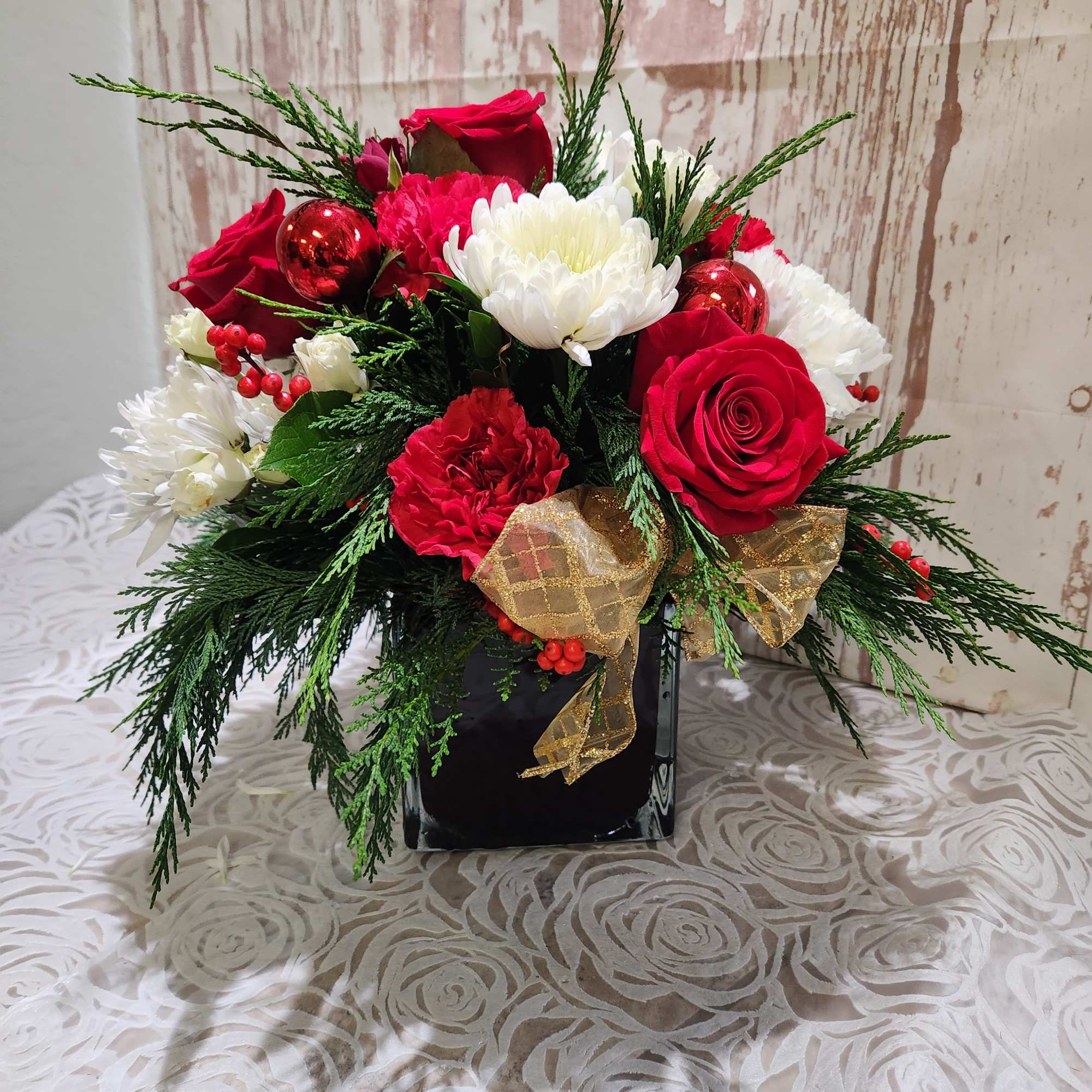 A sweet  Holiday mix of seasonal blooms and winter greens. 