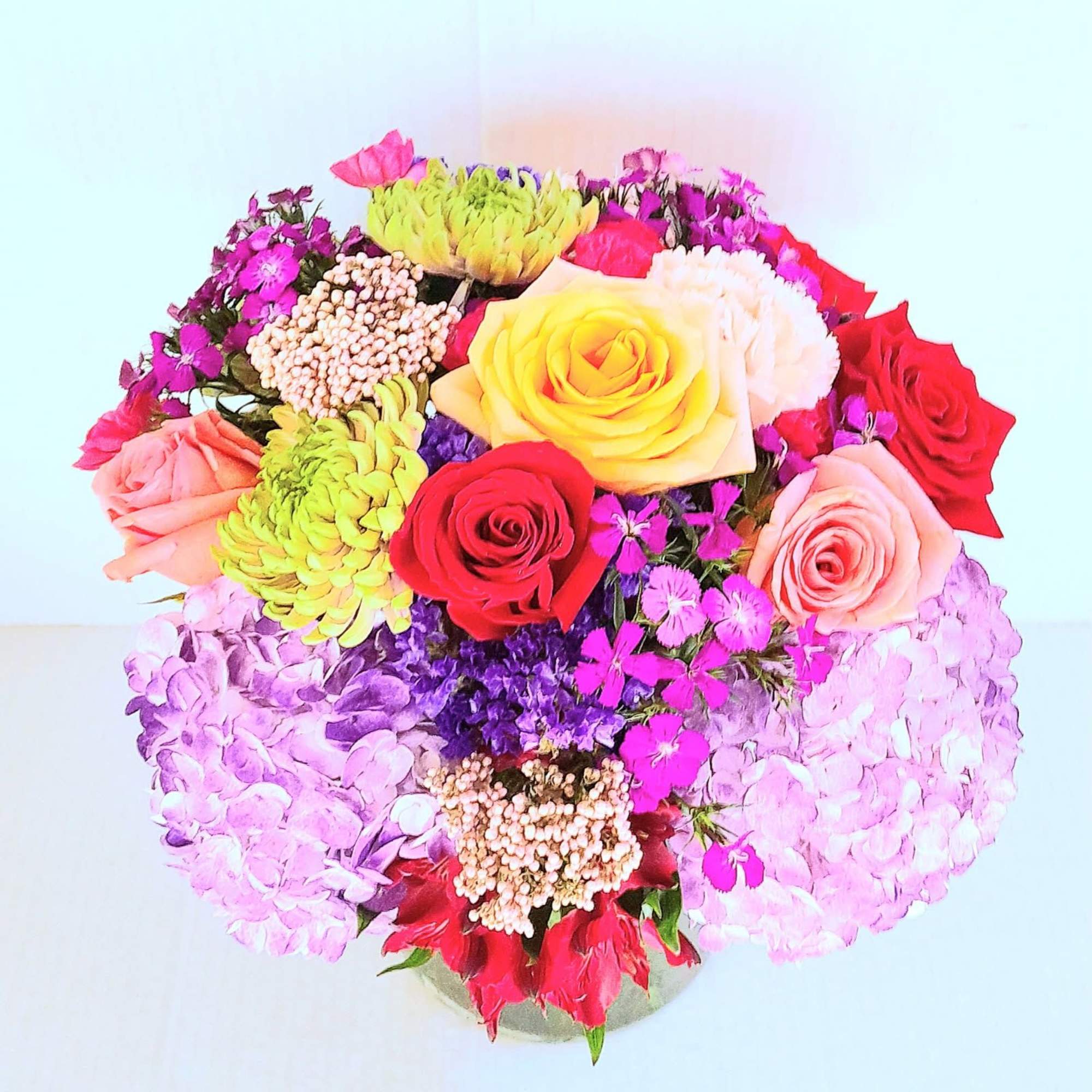 A vibrant and lush gift of assorted flowers and roses surrounded by