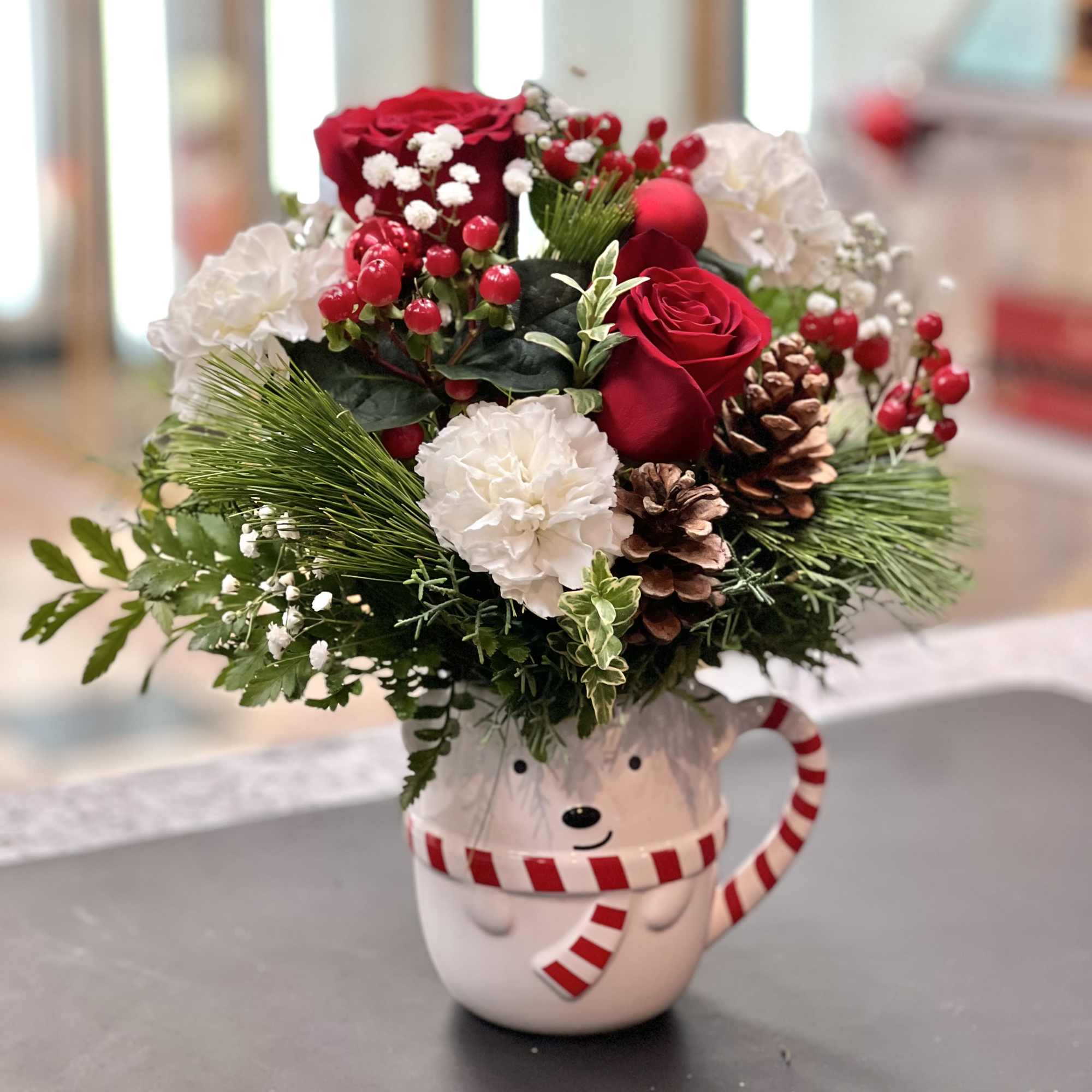 This cheerful red and white bouquet in an adorable bear cup will