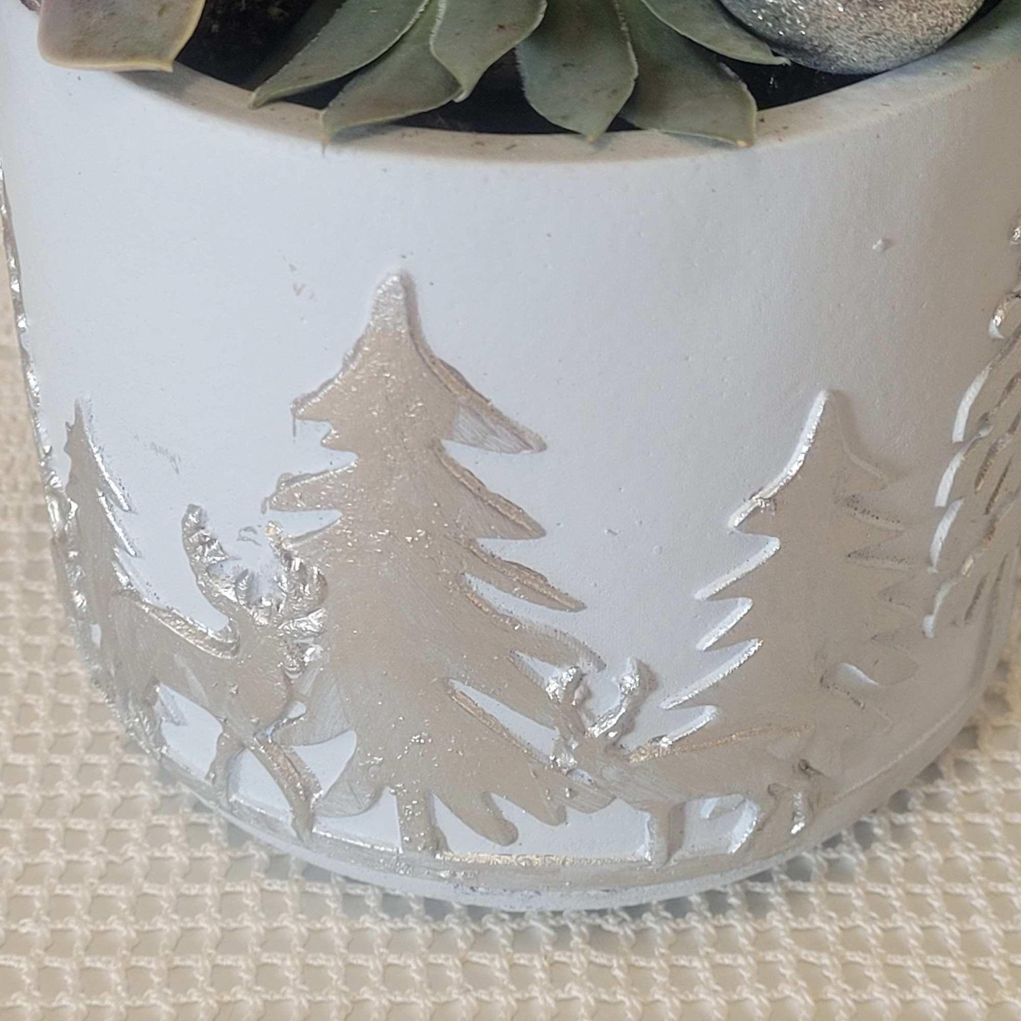 A festive container planted with succulents and faux holiday embellishments. Looks great