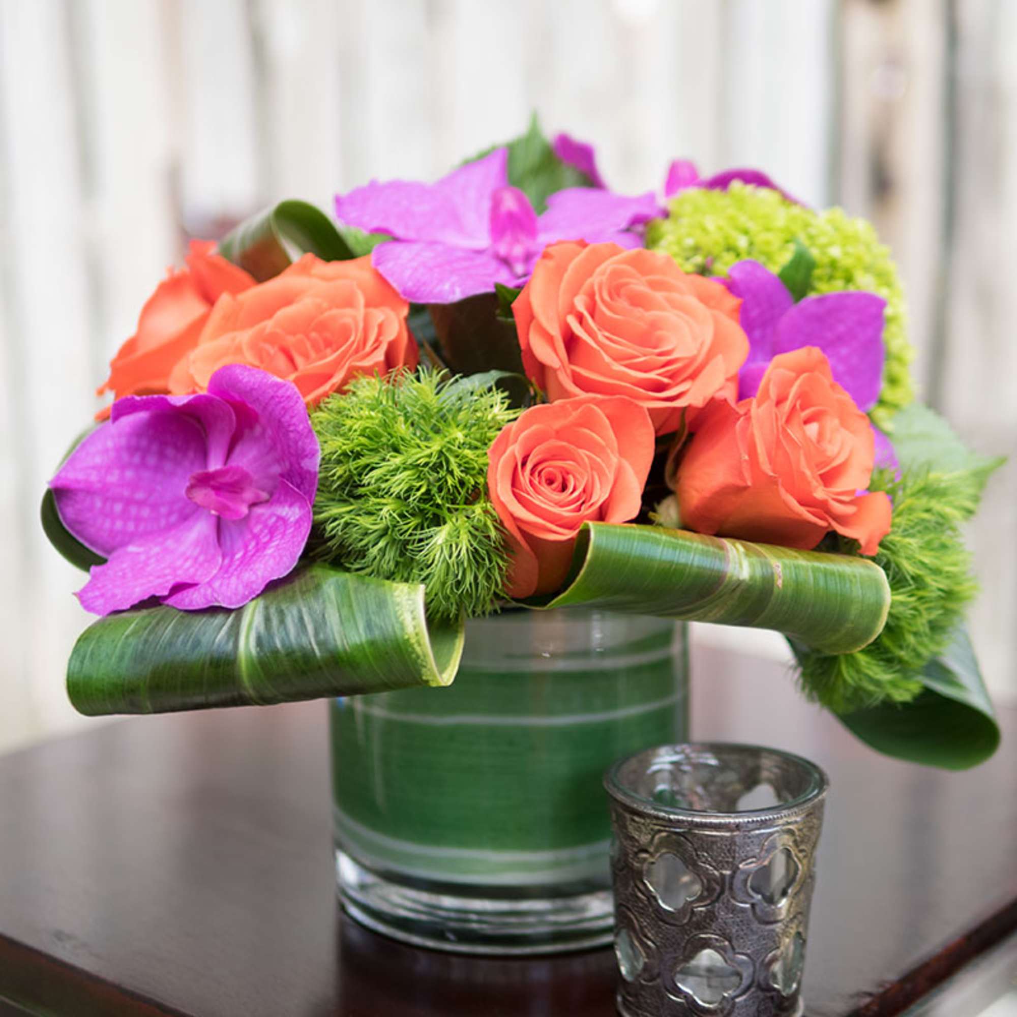 Pops of orange and pinks among green, roses, orchids dianthus and hydrangeas.