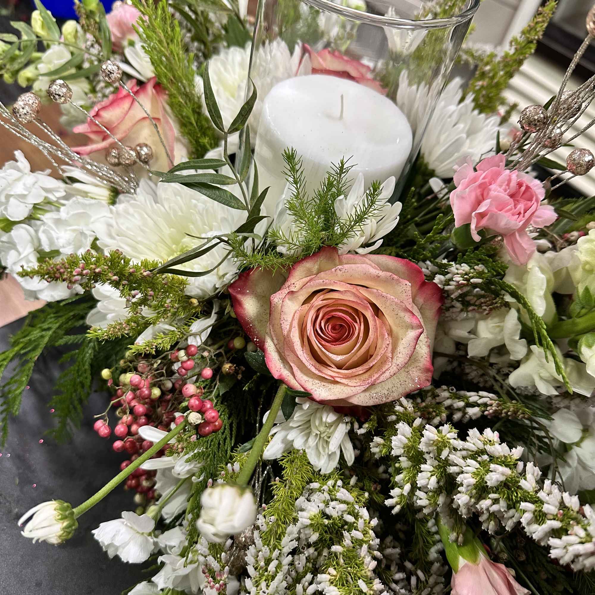 Beautifully designed holiday centerpiece with holiday themed florals and greenery adorned with