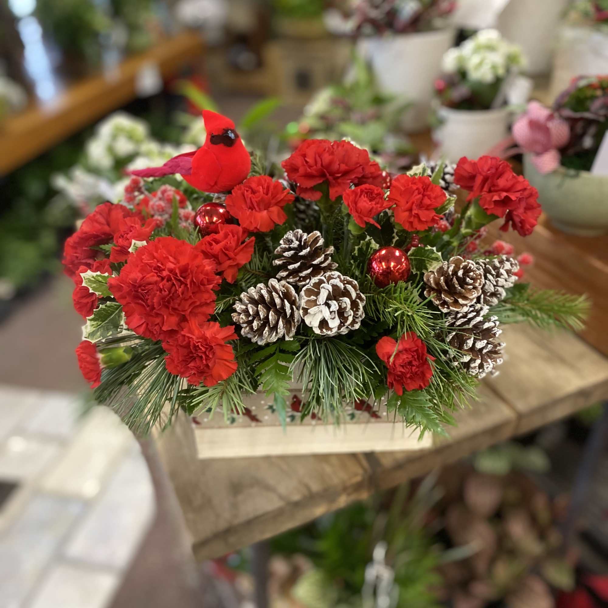 A bright and cheery cardinal sits atop this long lasting floral arrangement