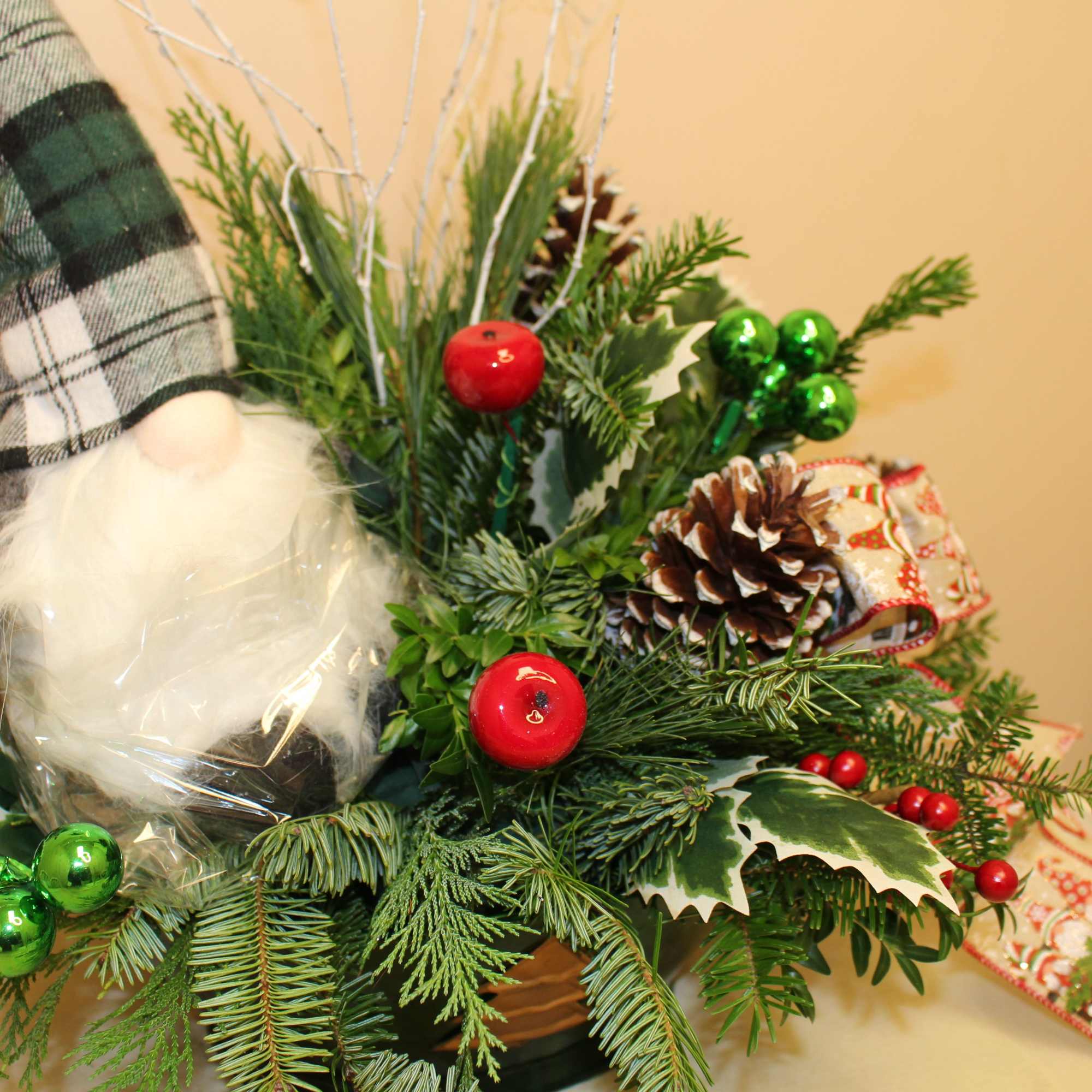 Jerome the gnome sits among evergreens, loving this long lasting arrangement. 