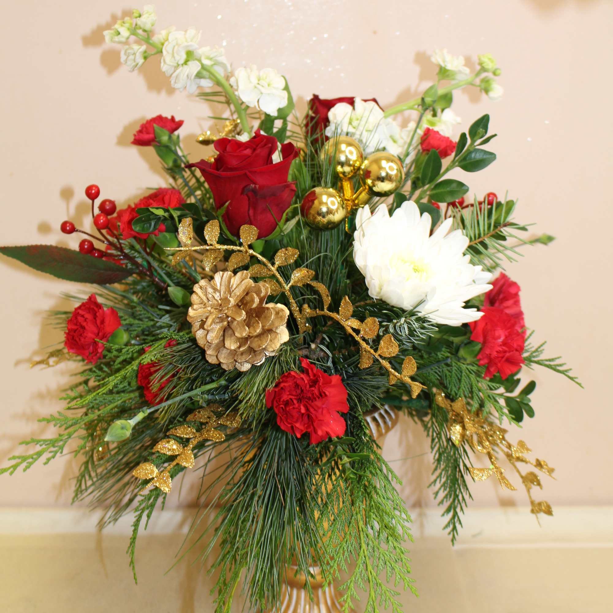  a gold pedestal is filled with a long lasting holiday arrangement.