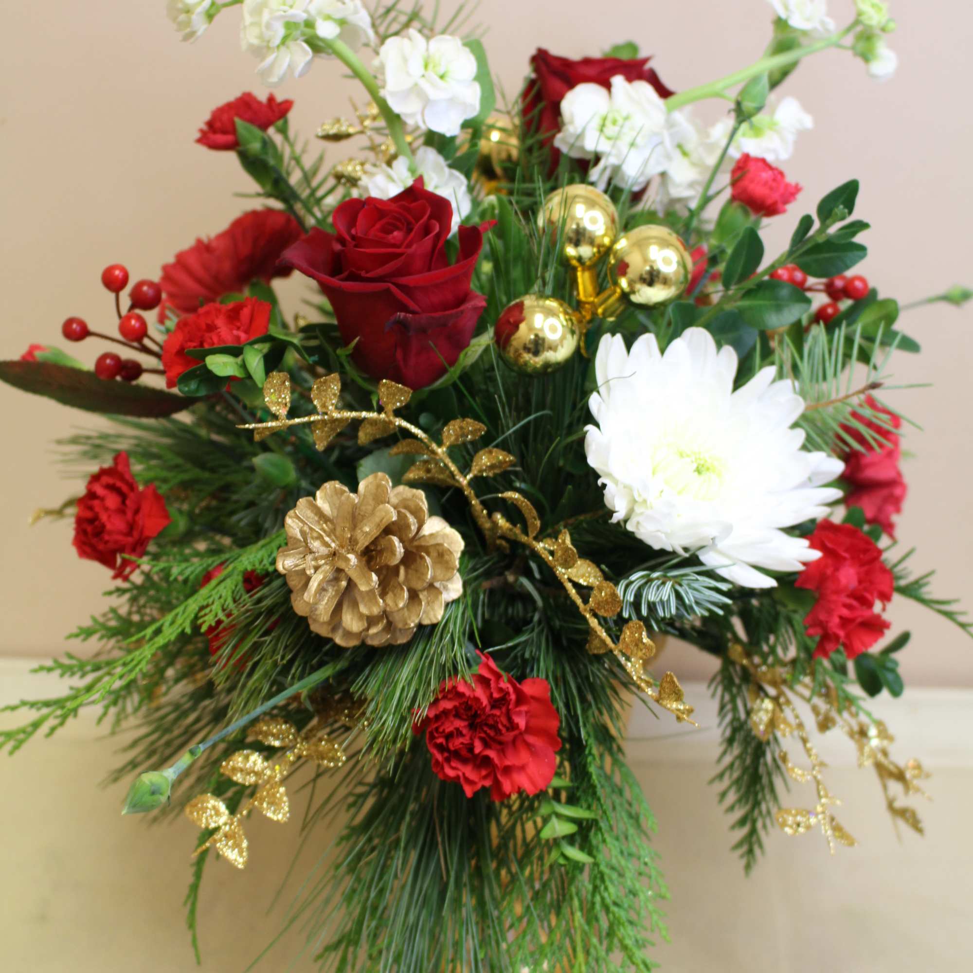  a gold pedestal is filled with a long lasting holiday arrangement.