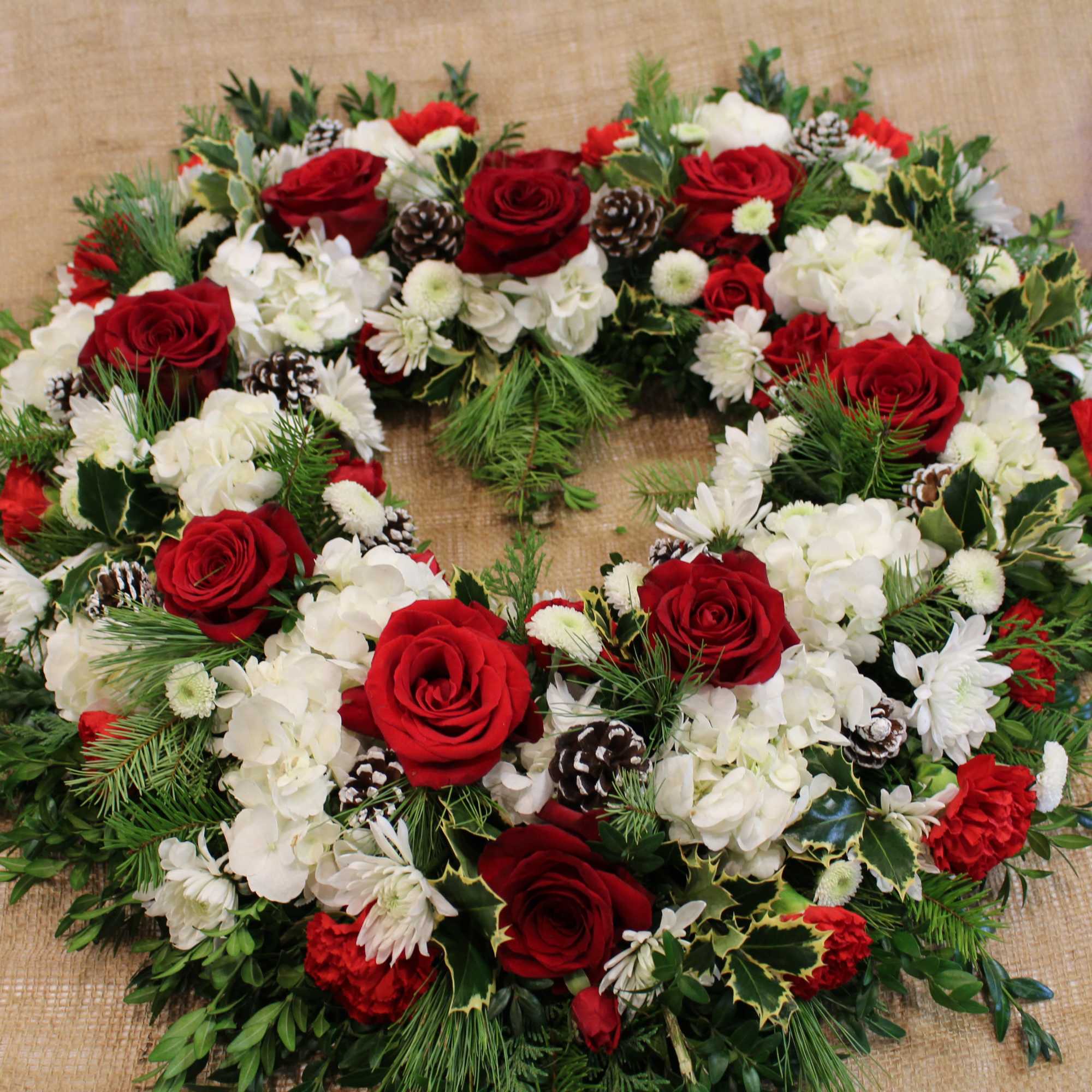 A beautiful arrangement of flowers shaped into a heart, seasonal greenery draped
