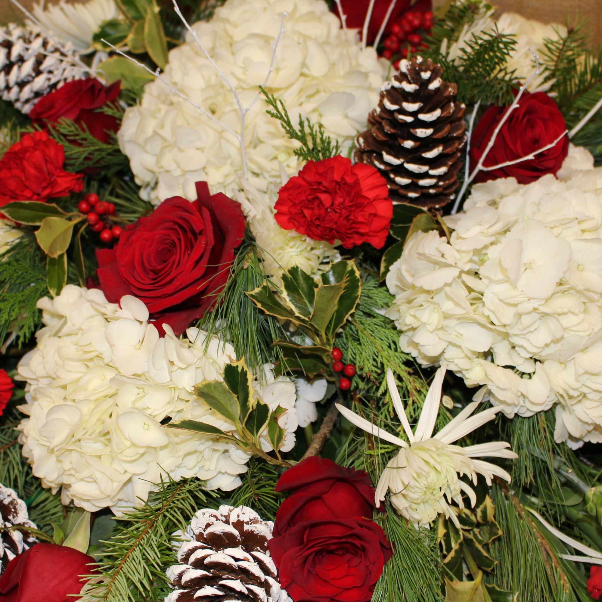 this is a breathtaking Casket spray filled with roses, carnations, hydrangea, pinecones