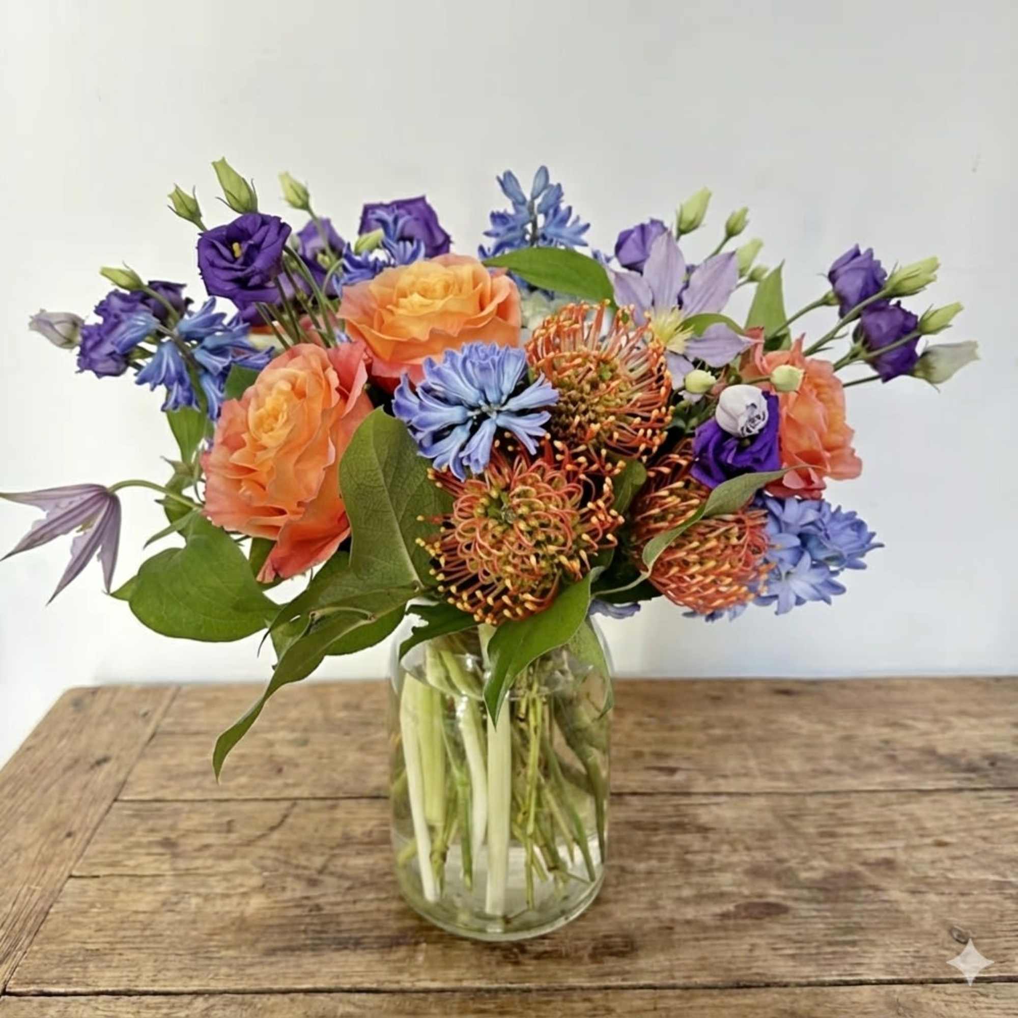 This arrangement is presented in a milk jar glass. It features bright