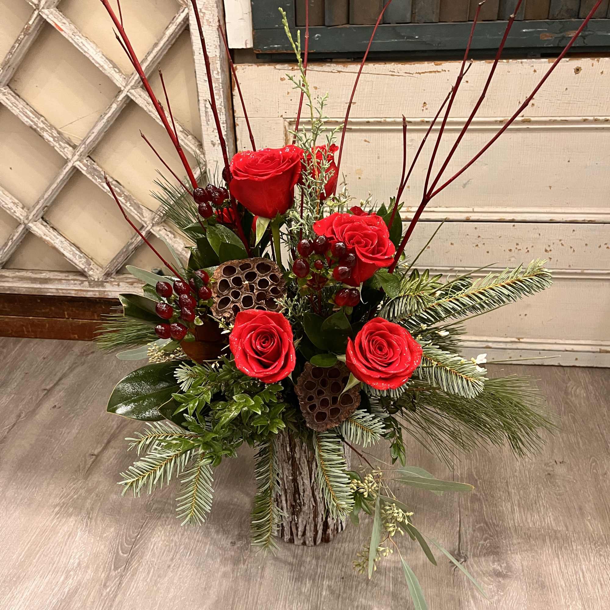 A rustic, bark enrobed vase is overflowing with fresh cut pine, cedar