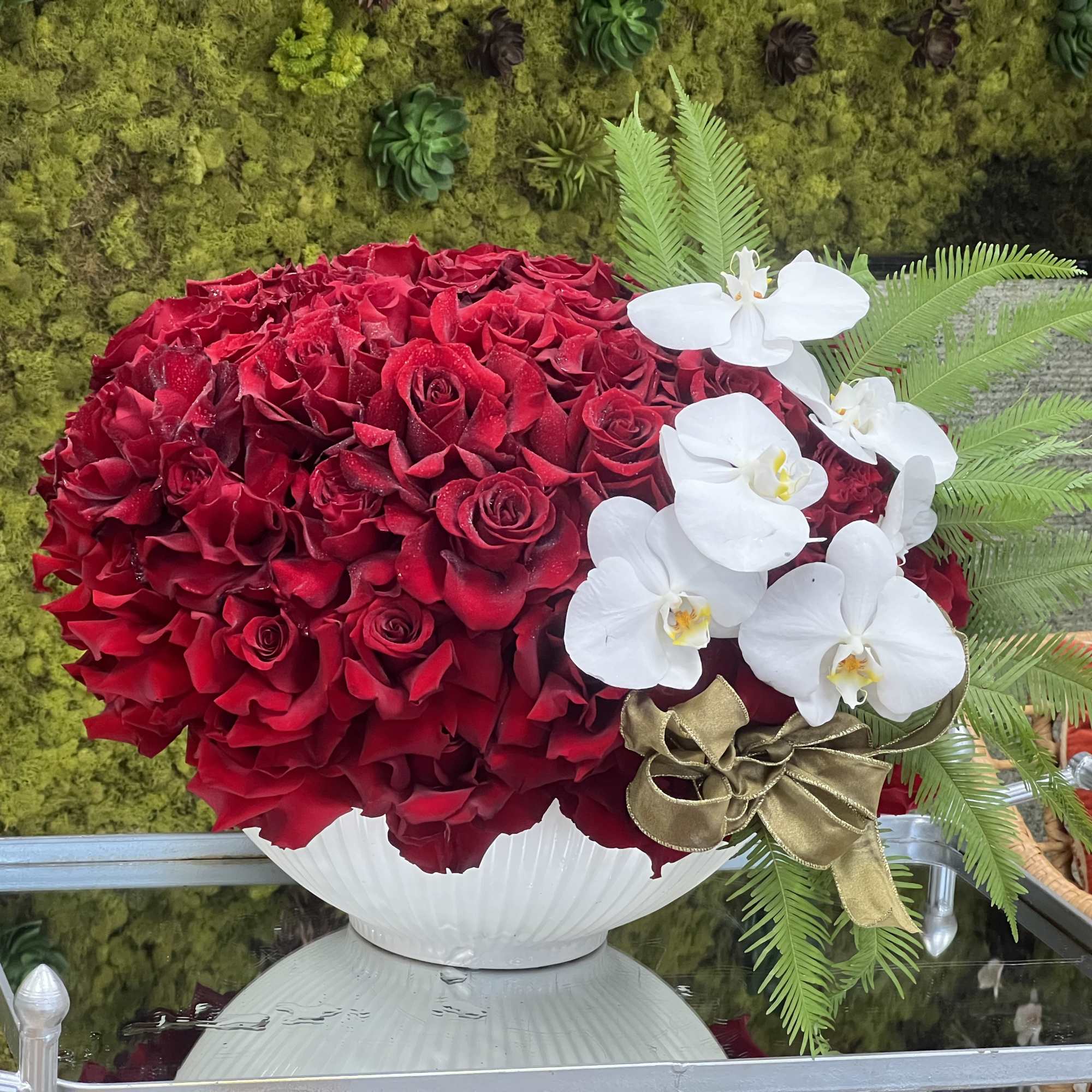 Two dozen gorgeous red roses are accented with darling pink orchids and