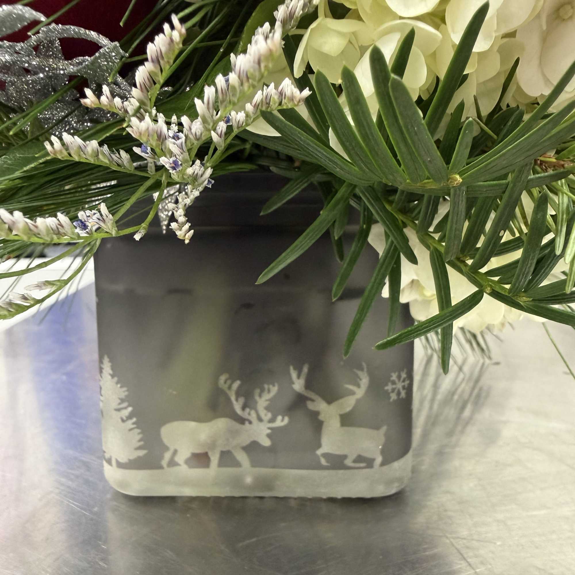 A beautiful winter arrangement designed in a glass cube with a reindeer