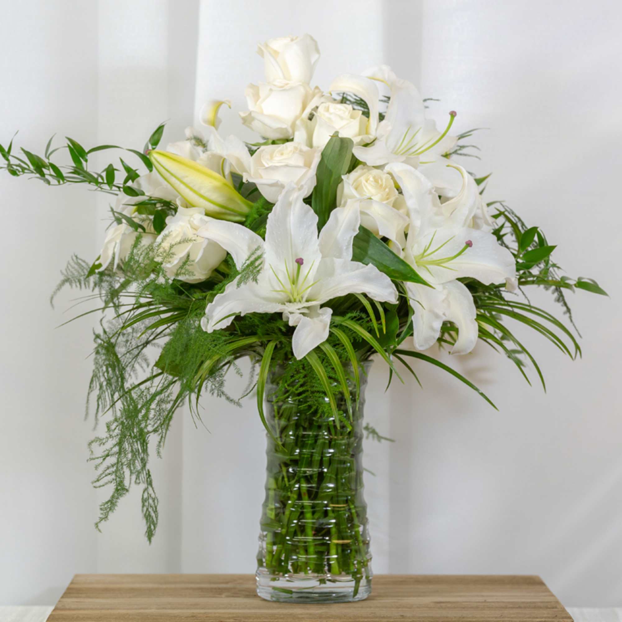 Casablanca white lilies complimented by stunning white roses and seasonal greens.